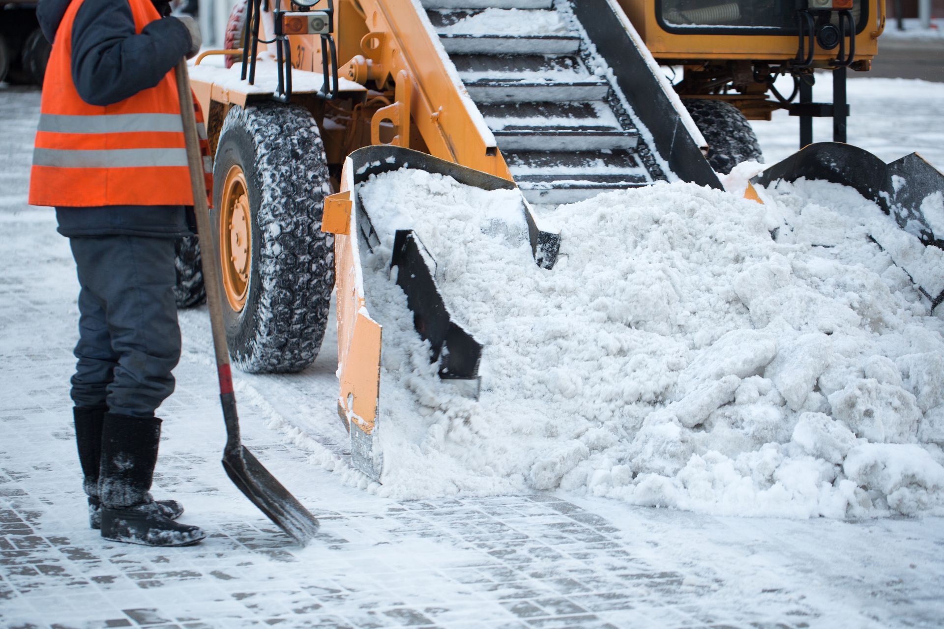 Tractor cleaning the road from the snow. Excavator cleans the streets of large amounts of snow in city. 
