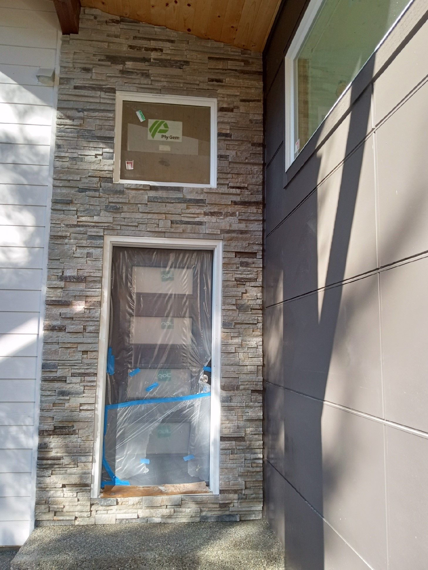 A stone wall with a door and a window on the side of a house.Gray Smith Masonry Logo Icon