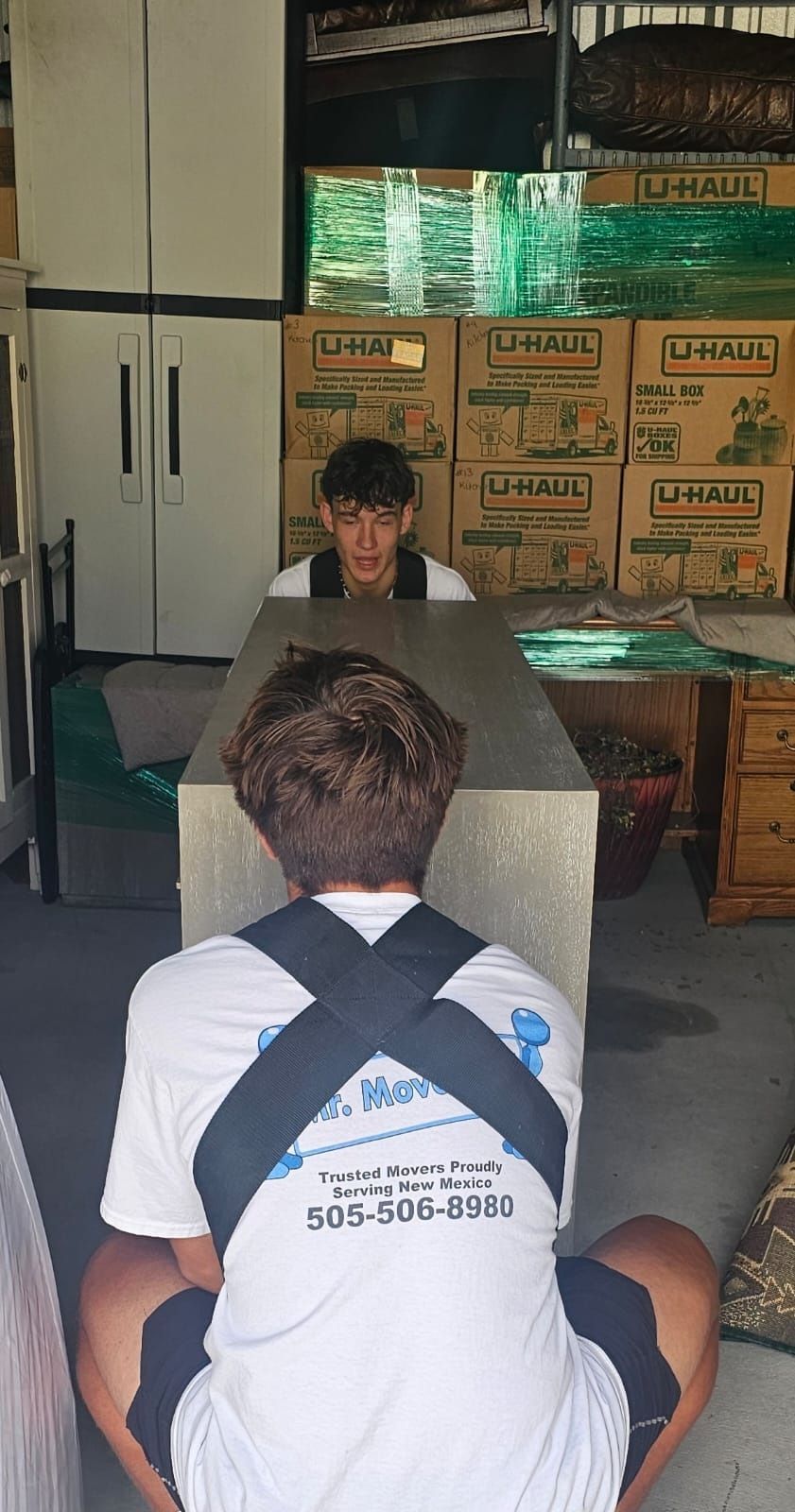 A man is sitting at a table in front of a stack of boxes.