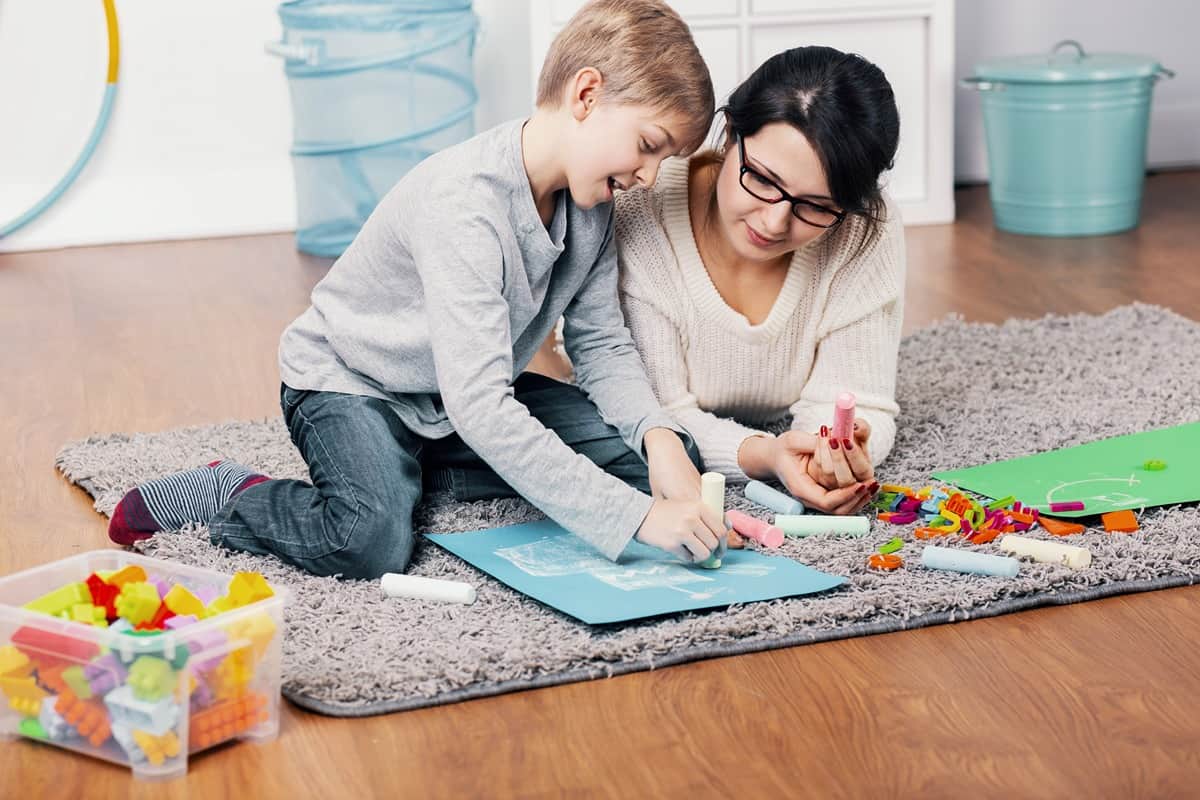 Mother and child coloring with chalk on a rug on the floor near Richmond, Kentucky (KY)