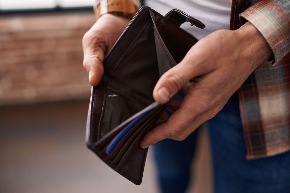 Hands holding an open brown wallet with visible cards indoors