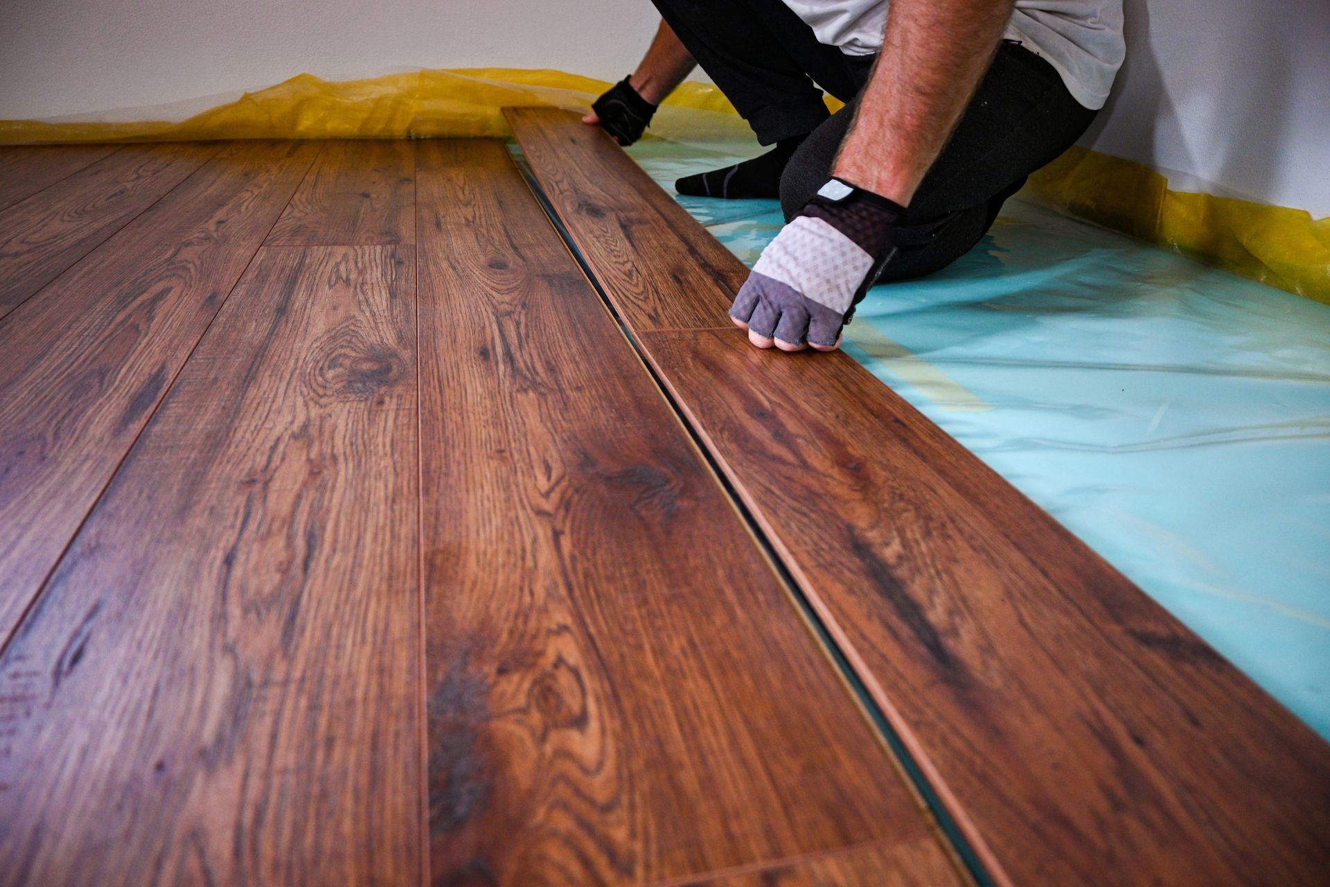 Person installing dark wood laminate flooring.
