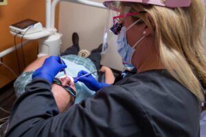 A dentist is examining a patient 's teeth in a dental office.