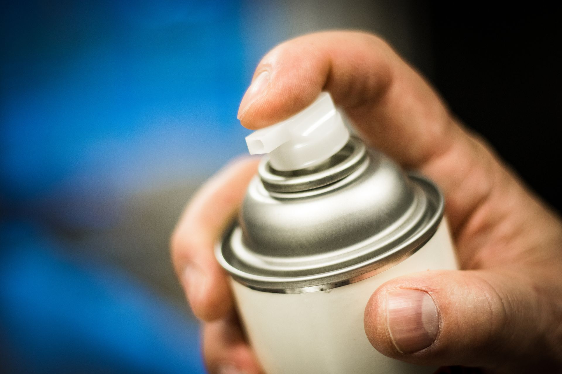 A person is holding a spray can in their hand.