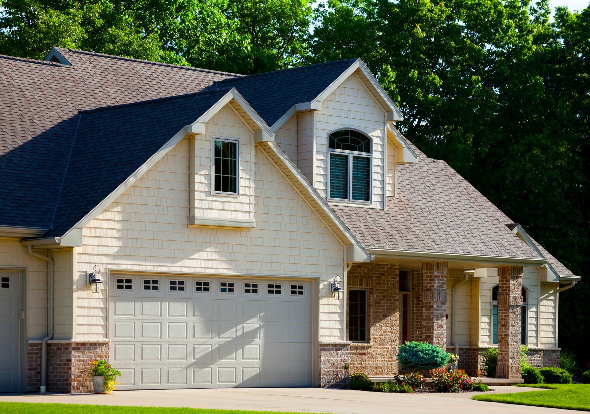 A white house with a brown roof and a white garage door