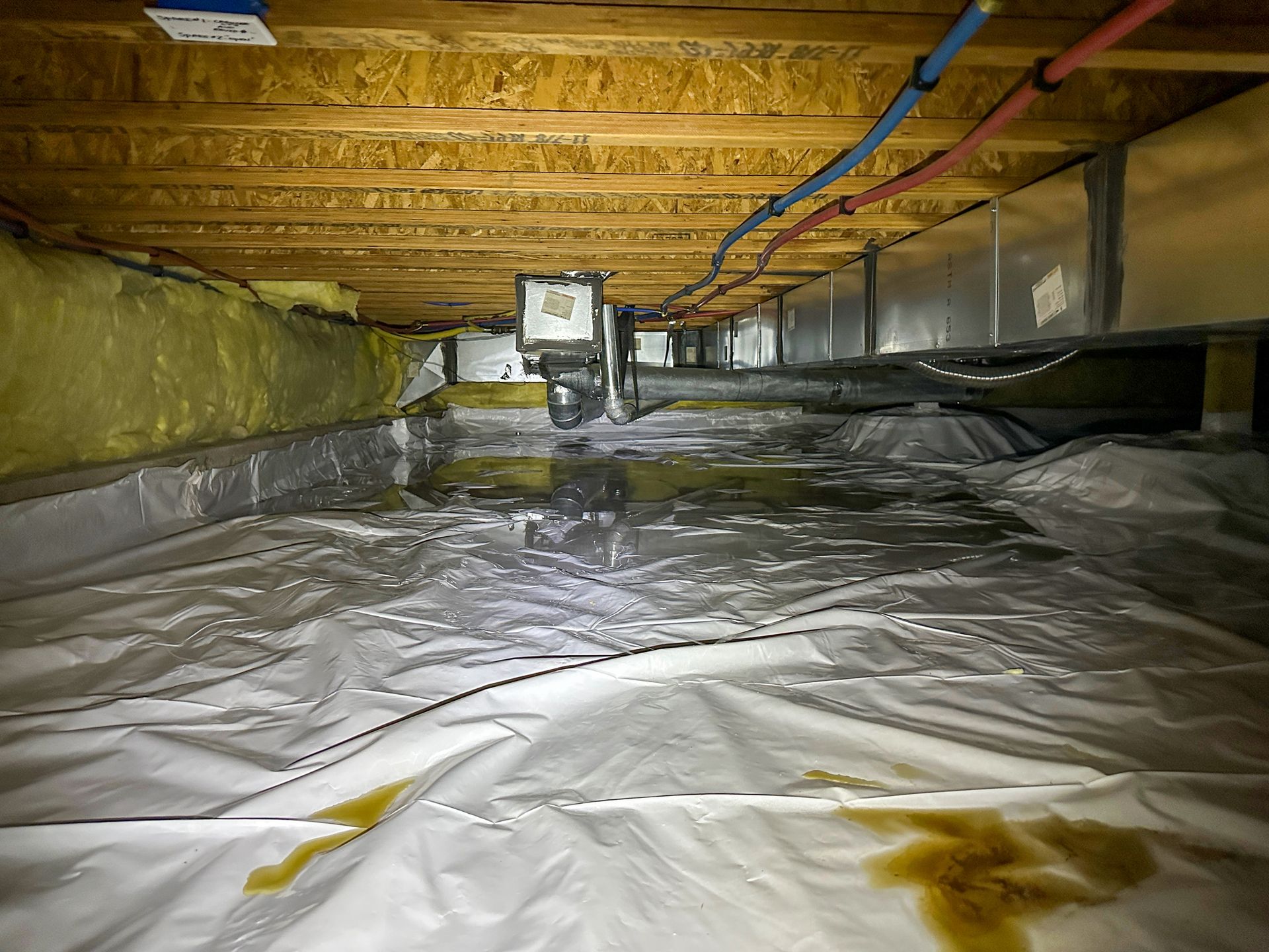 A crawl space with a lot of pipes coming out of it.