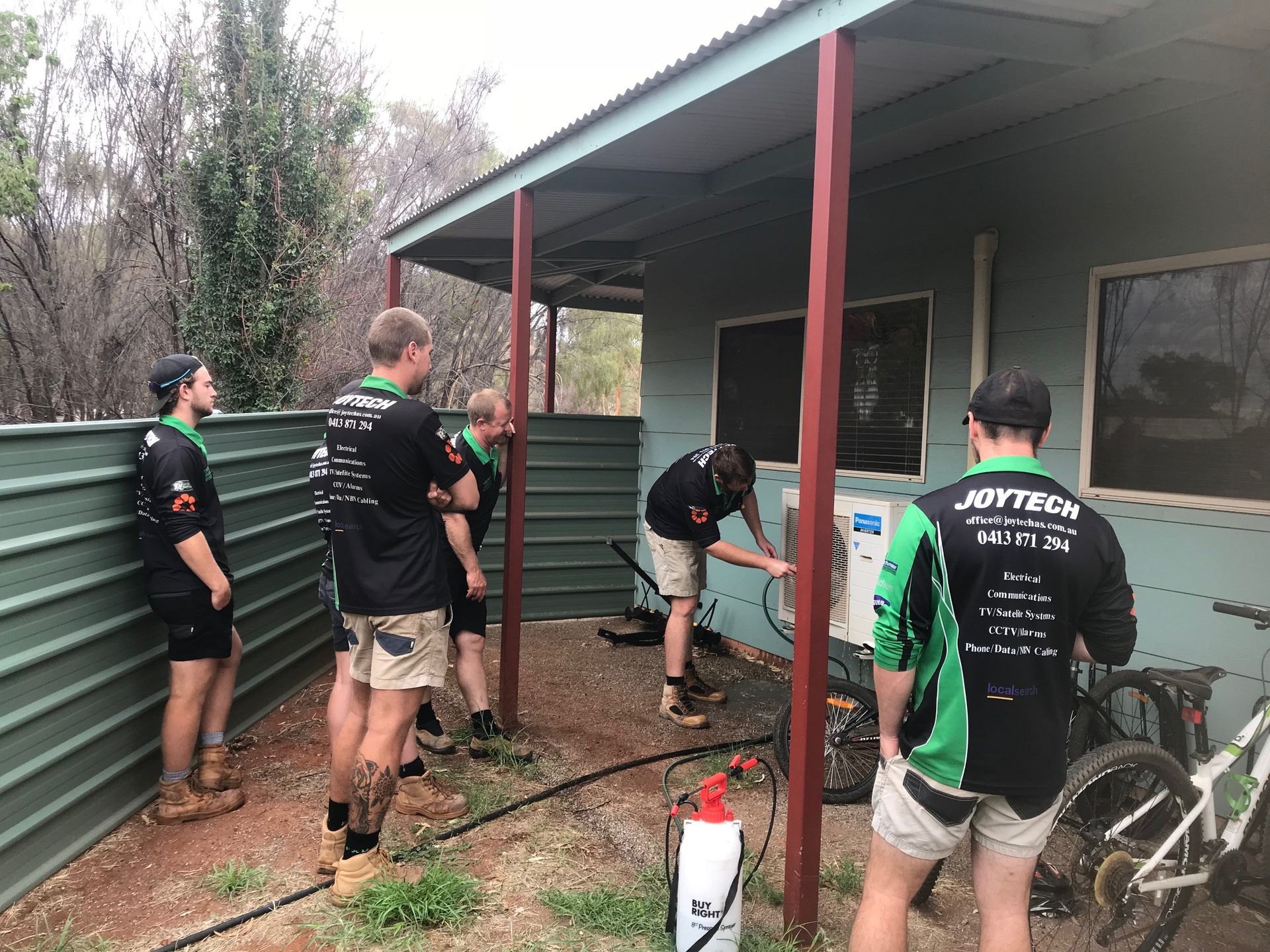 A Group Of Men Are Standing Outside Of A Building — Joytech In Ciccone, NT