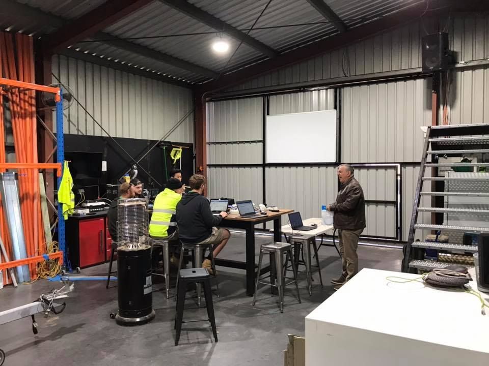 A Group Of People Are Sitting Around A Table In A Workshop — Joytech In Ciccone, NT