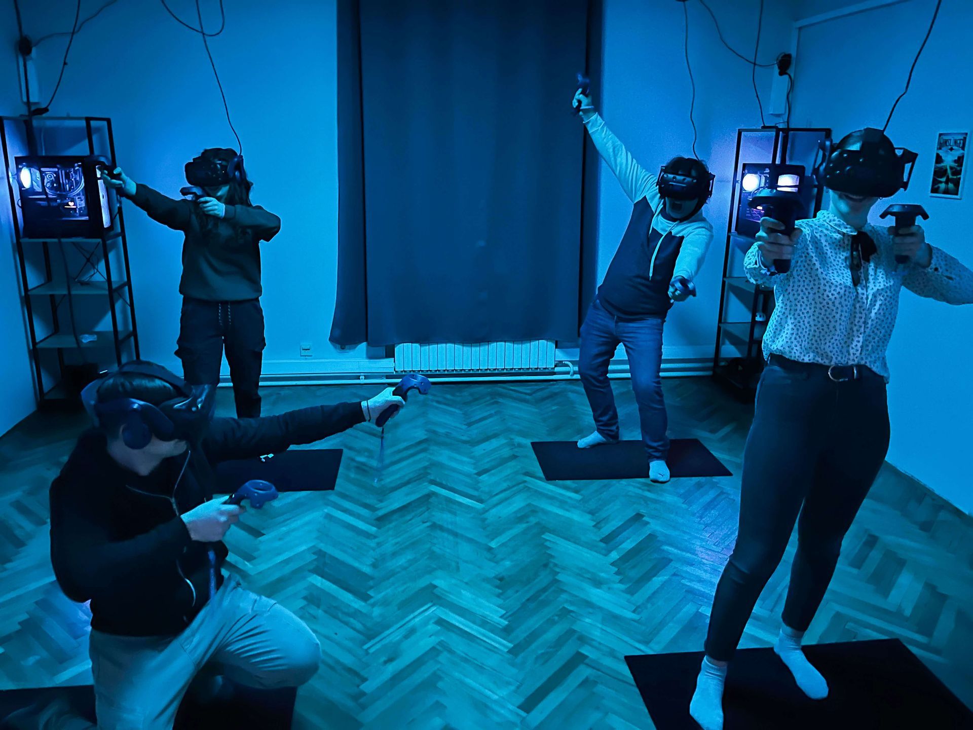 4 players standing in one room with a virtual reality headset on their heads and VR controllers in their hands