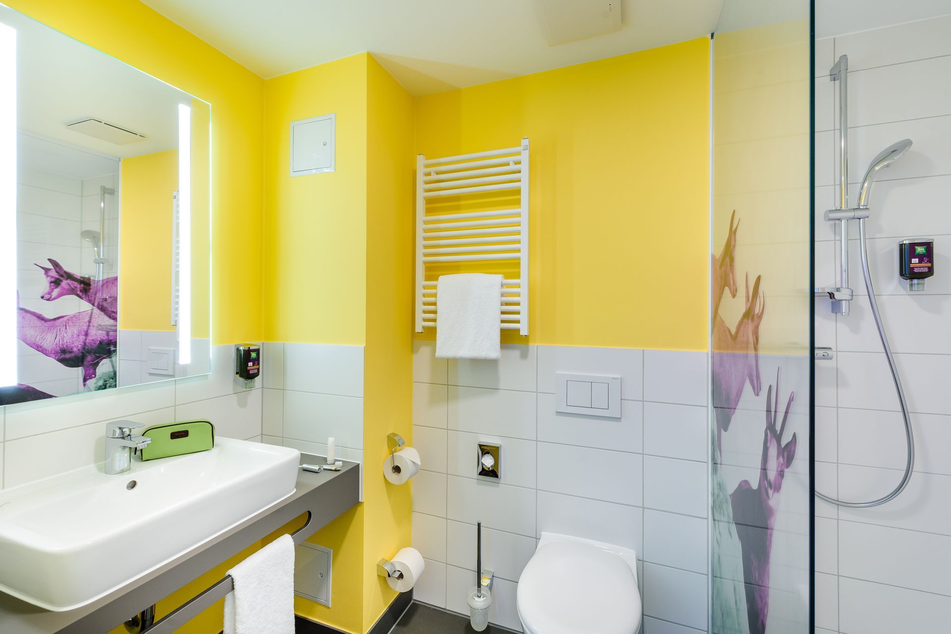 Hellgelbes Badezimmer mit Waschbecken, Toilette, Handtuchheizkörper und Duschkabine aus Glas