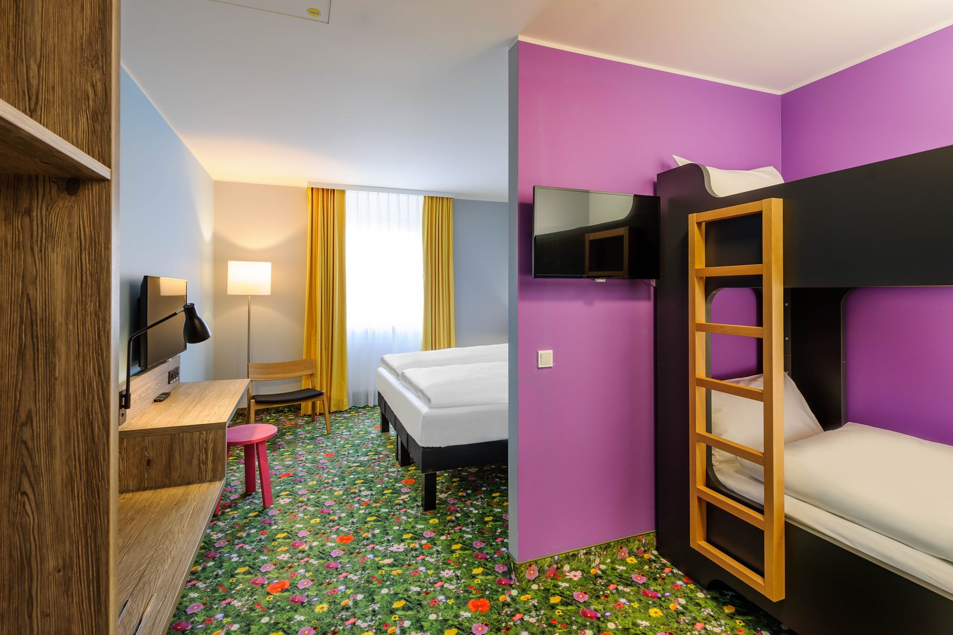 Modernes Hotelzimmer mit Etagenbetten, Einzelbett, lila Wänden und geblümtem Teppich.
