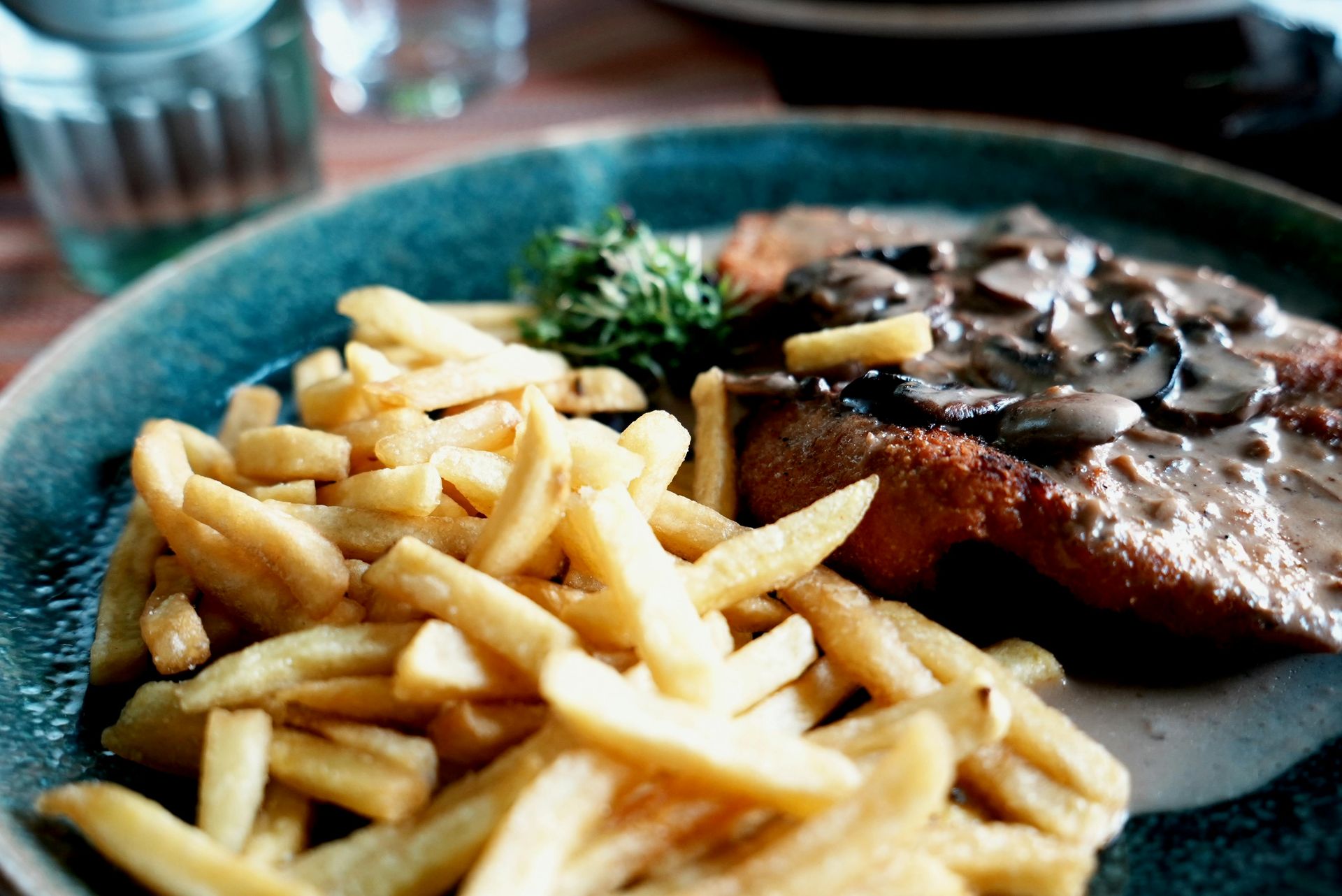 Steak mit Pilzsoße und Pommes frites auf blauem Teller