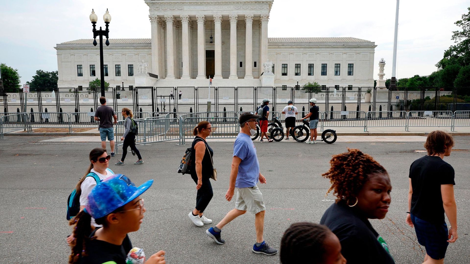 People walking across a plaza in front of the U.S. Supreme Court building