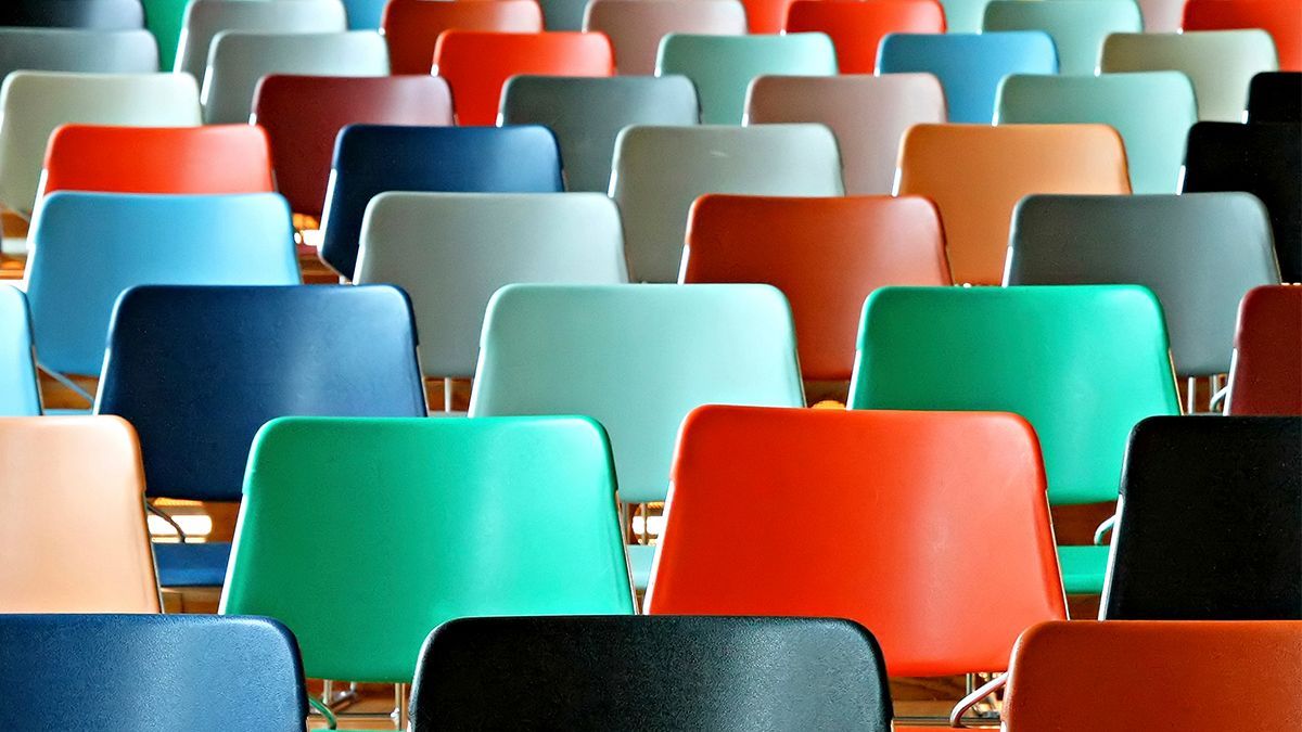 Rows of empty colorful plastic stadium seats in red, teal, blue, black, and orange