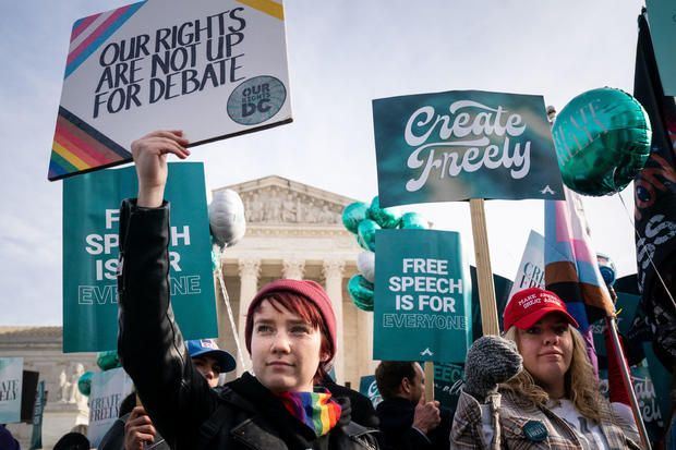 Protesters holding signs for free speech and debate outside a government building