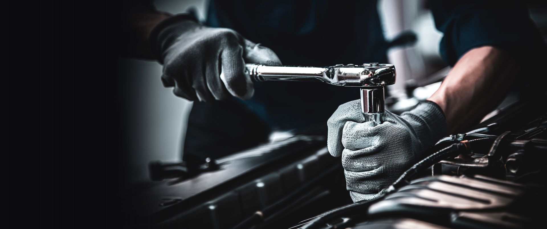 A man is laying on the ground working under a car.