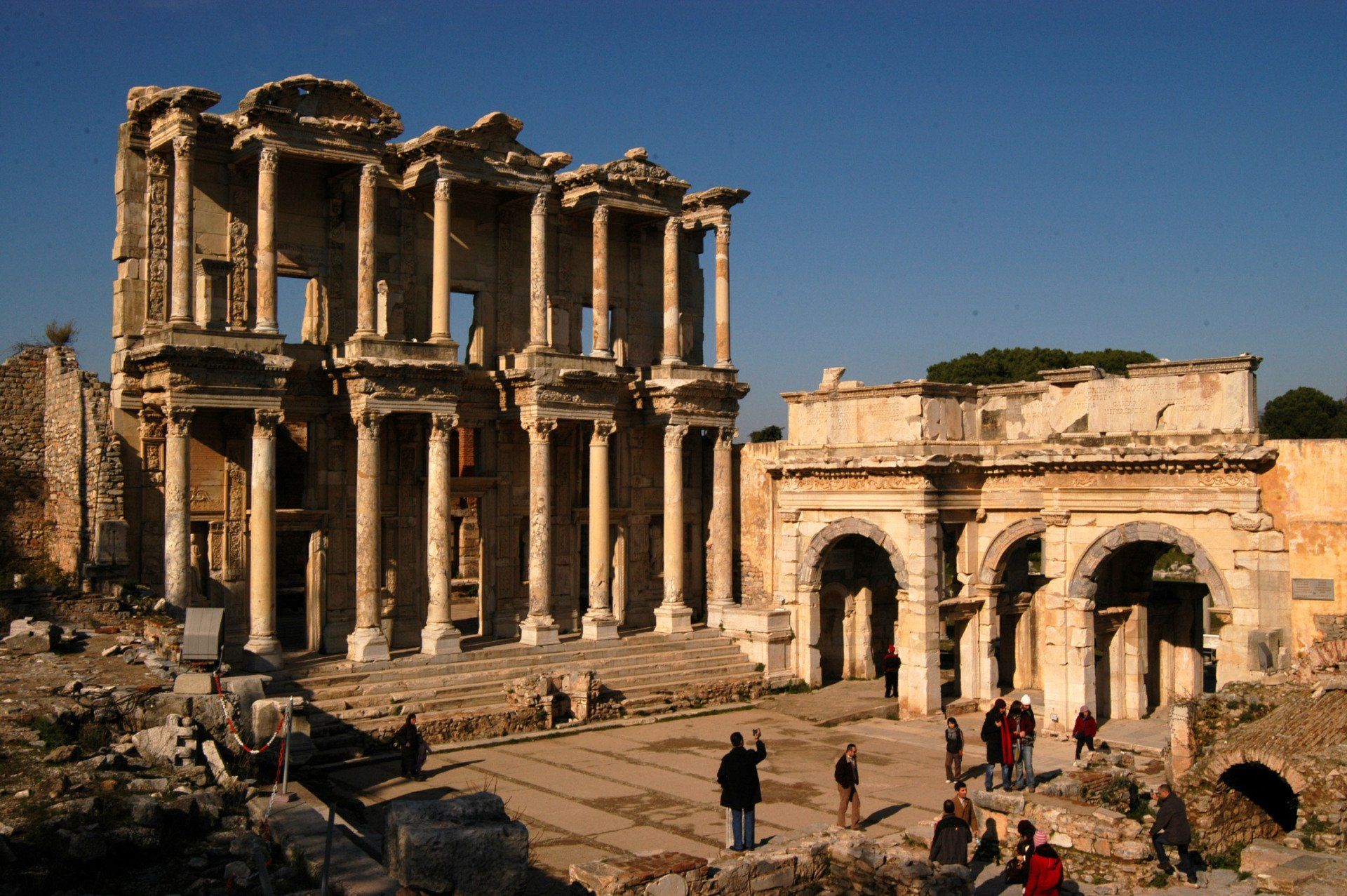 Ruins of the ancient city of Ephesus, with the iconic Celsus Library and visitors exploring the site.
