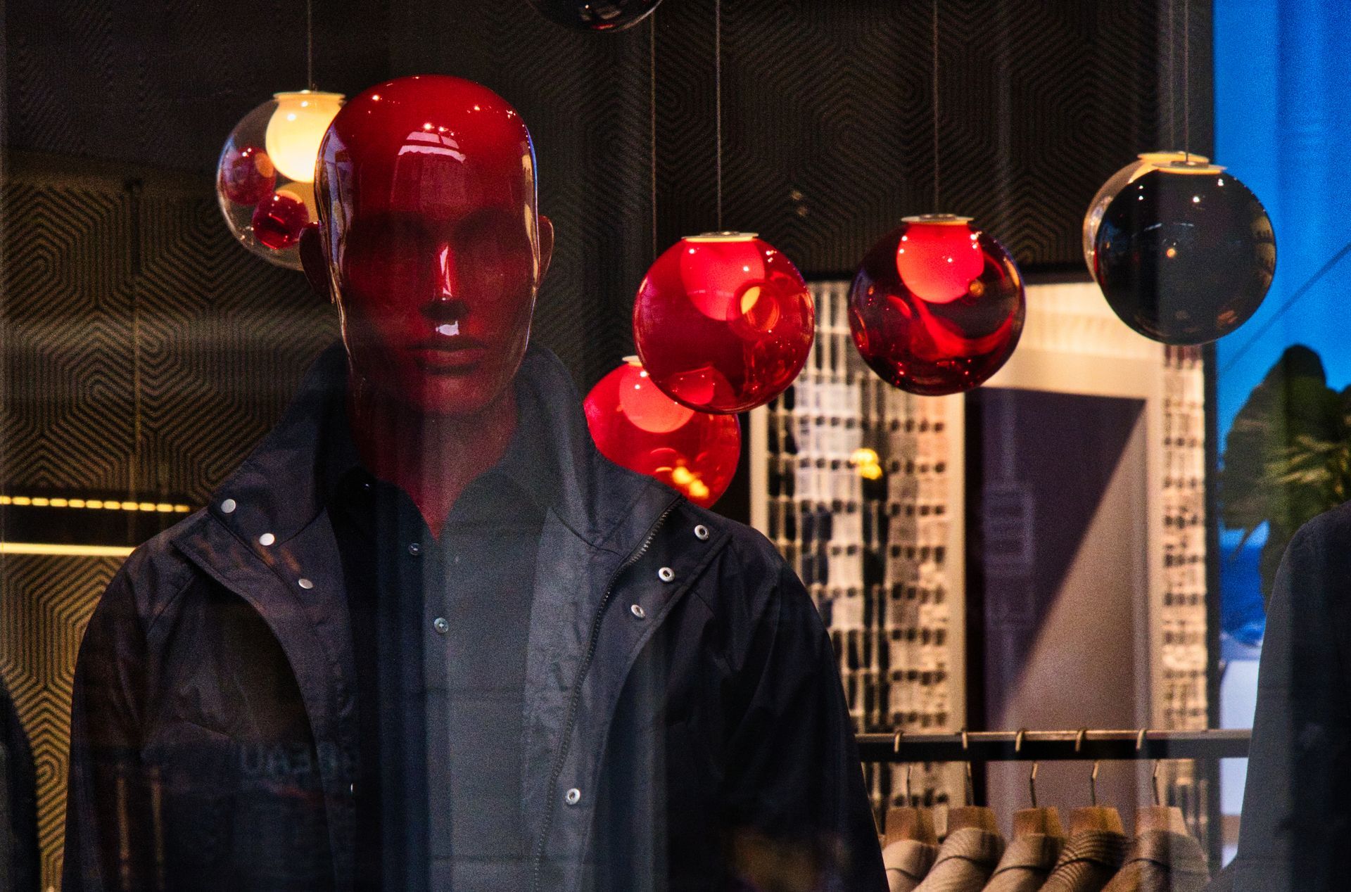 Mannequin with red face red glass spheres in a dimly lit display window