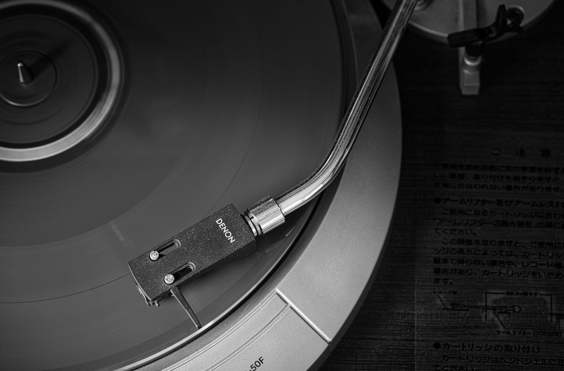 Close-up of a turntable needle on a spinning vinyl record in black and white