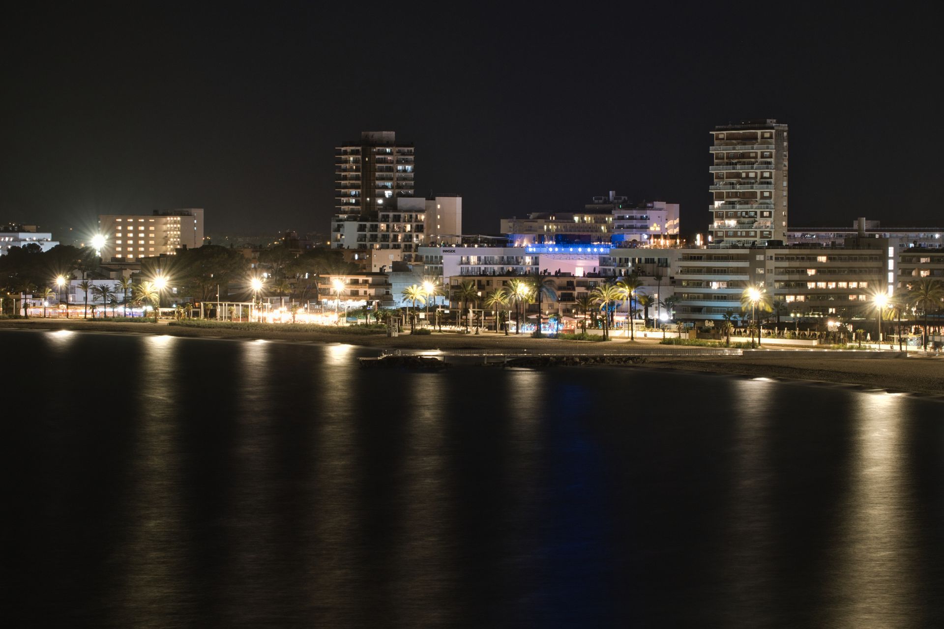 Nighttime city skyline with bright waterfront lights reflected on dark water