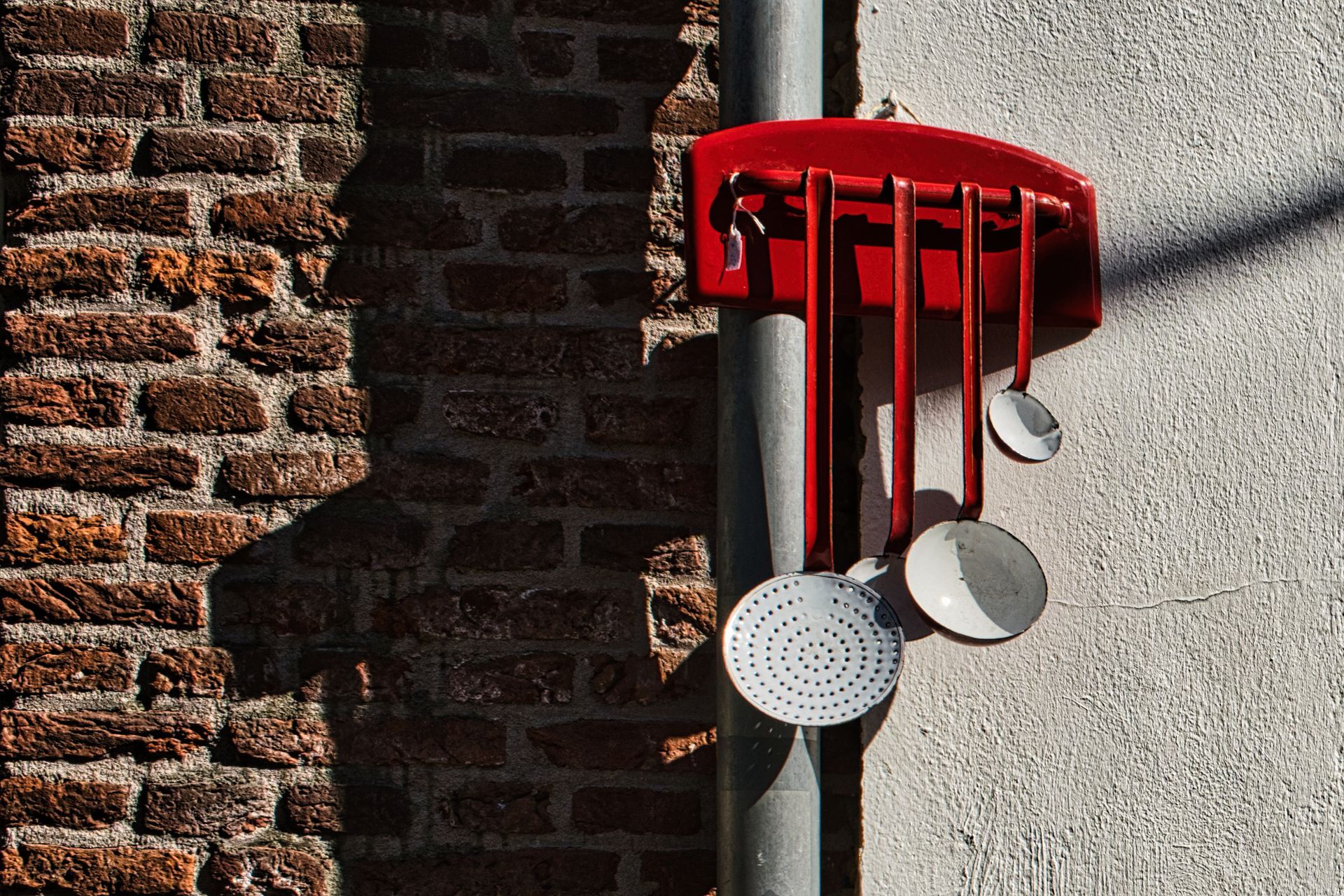 Red utensils a brick wall and white stucco wall