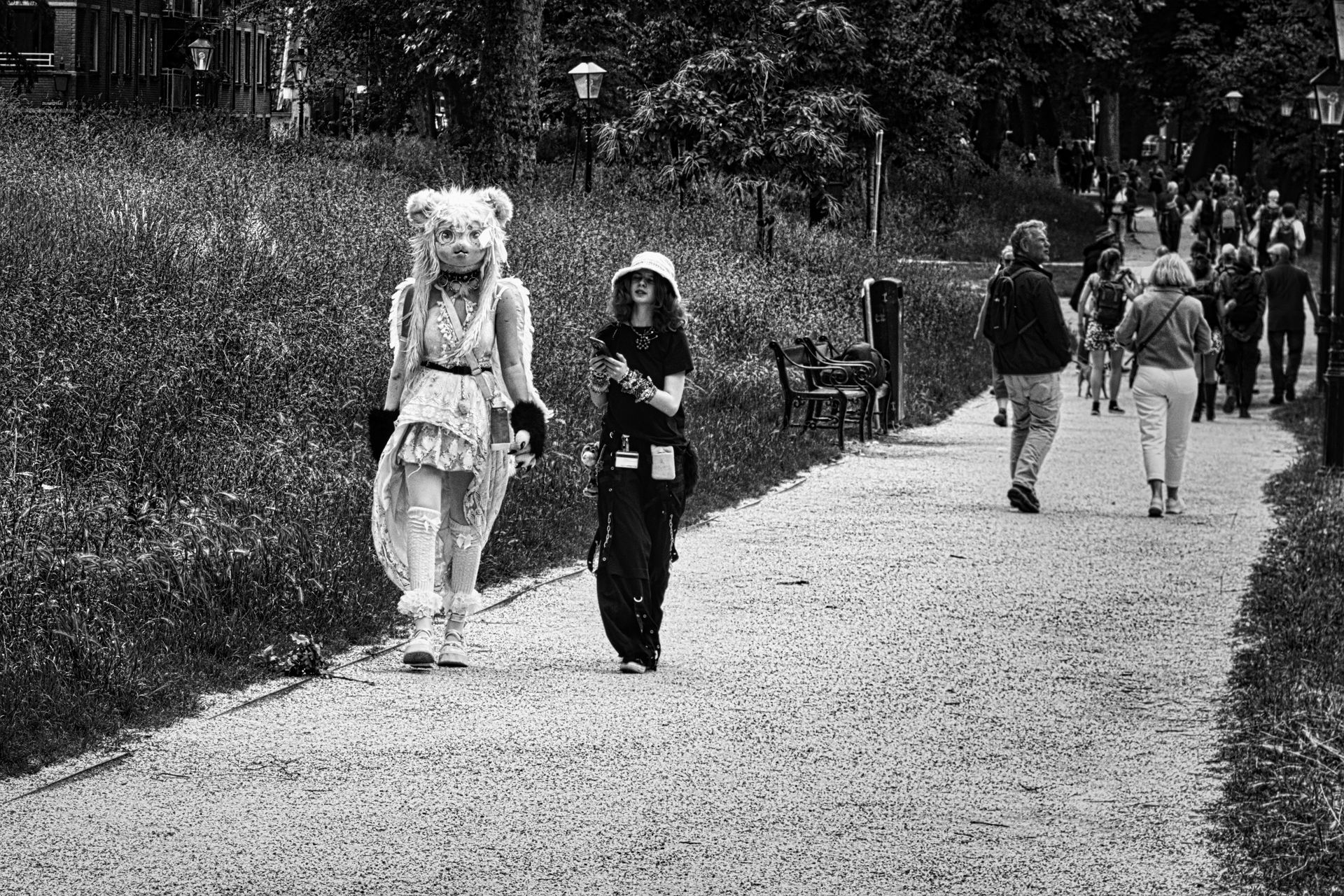 Two costumed people walking along a park path with others in the background