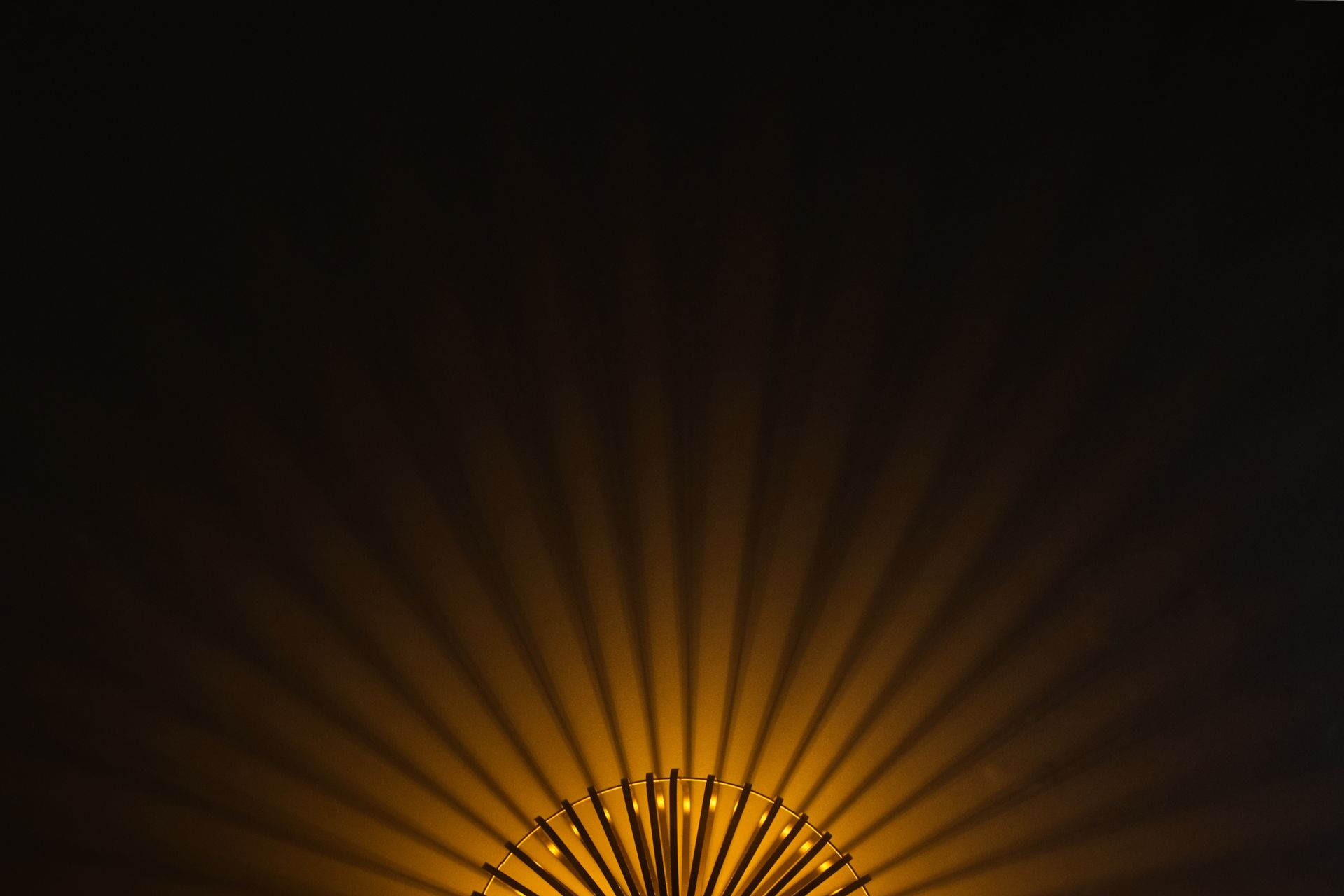 Orange fan-shaped light rays on a dark background, like a sunrise or illuminated decorative display.