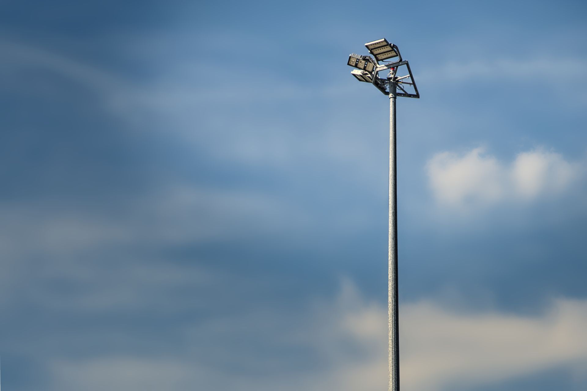 Tall stadium floodlight against a cloudy blue sky