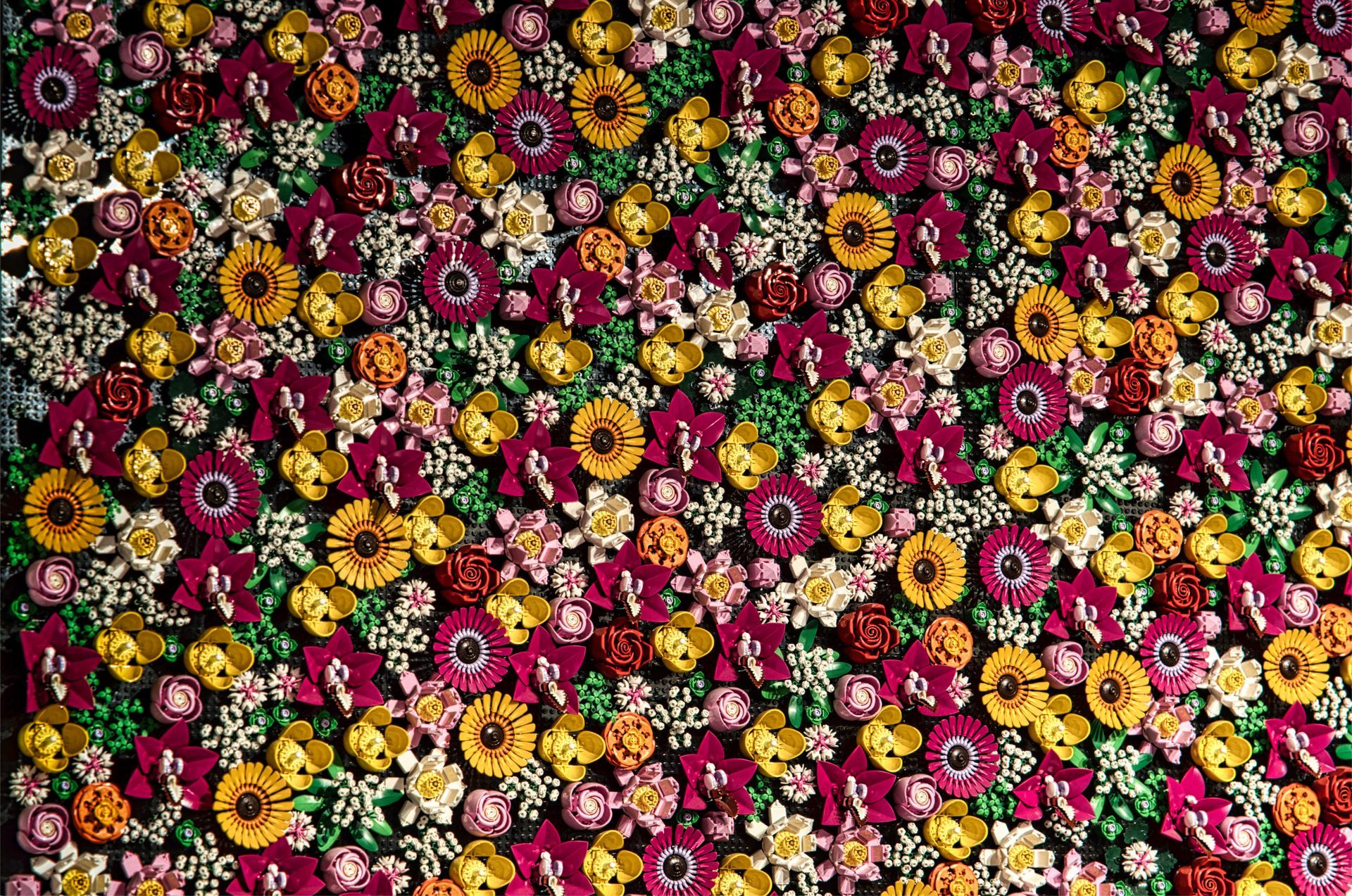 Dense floral pattern of colorful flowers in pink, yellow, red, and white made out of Lego bricks