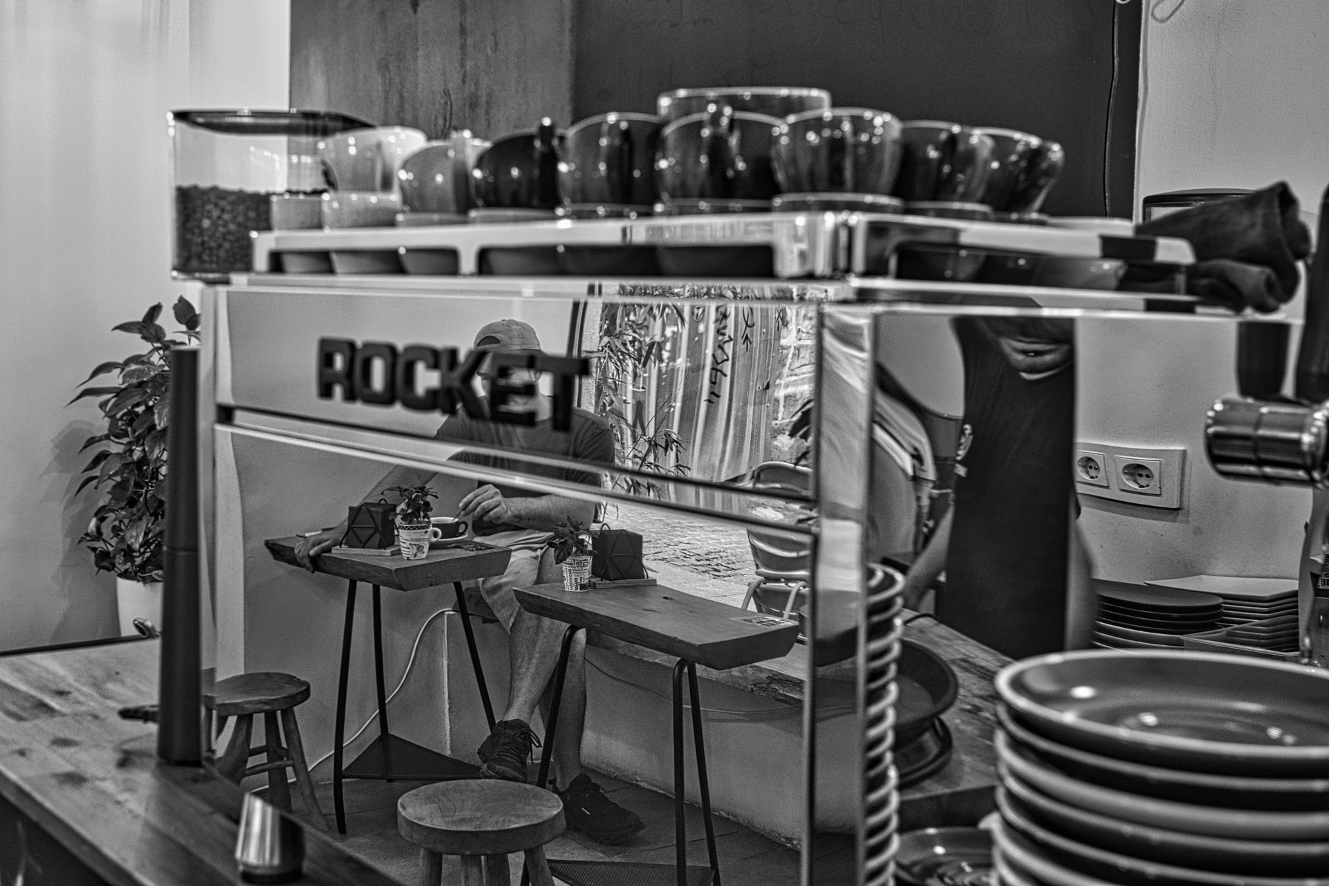 Indoor coffee counter with cups, stools, and a “ROCKET” sign