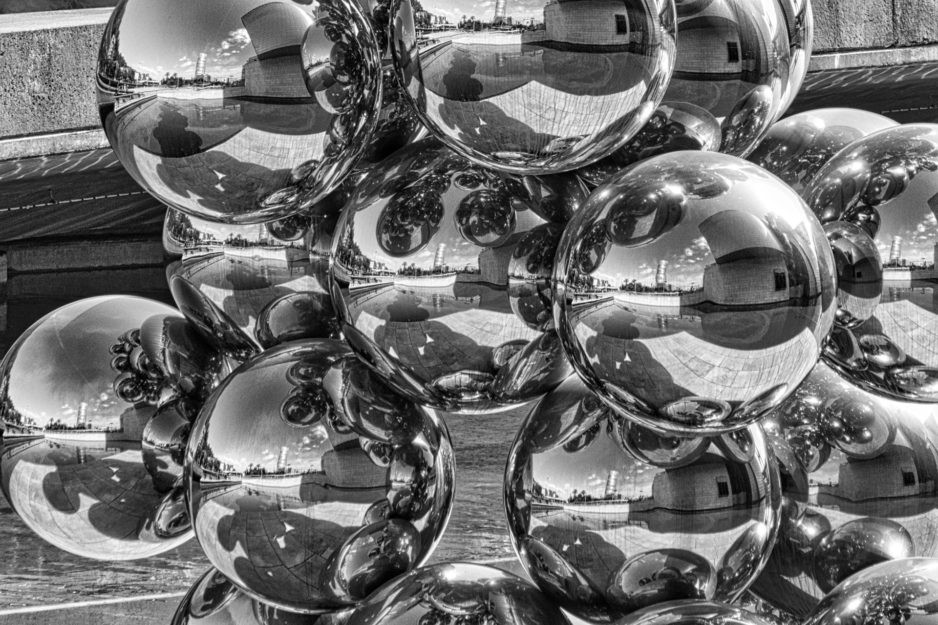 Reflective silver spheres clustered together, mirroring a city street and people nearby.