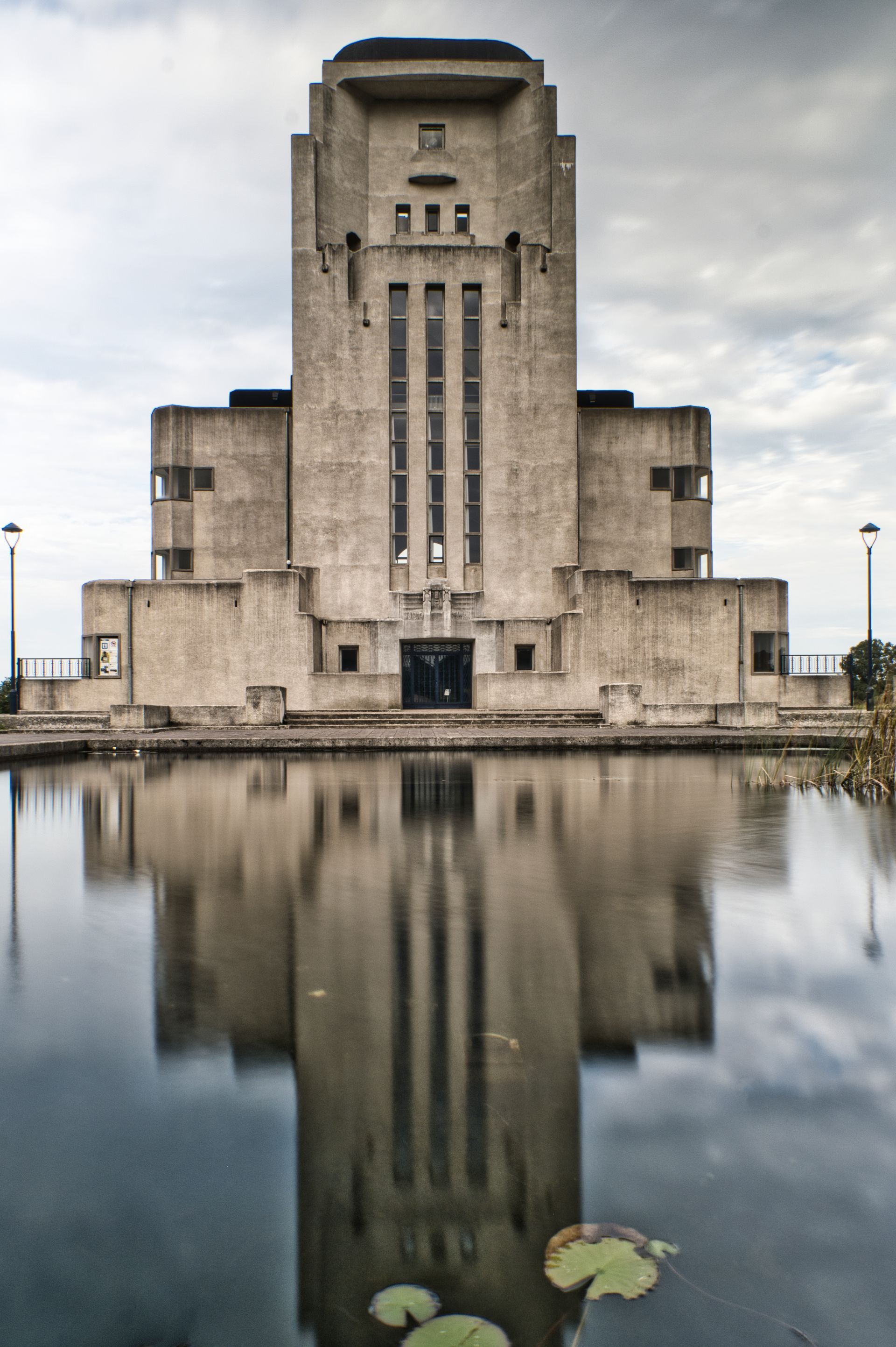 Art Deco building reflected in a calm pool under a cloudy sky