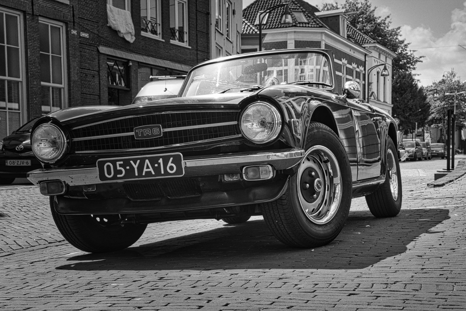 Triumph TR6 vintage car parked on a cobblestone street in front of buildings
