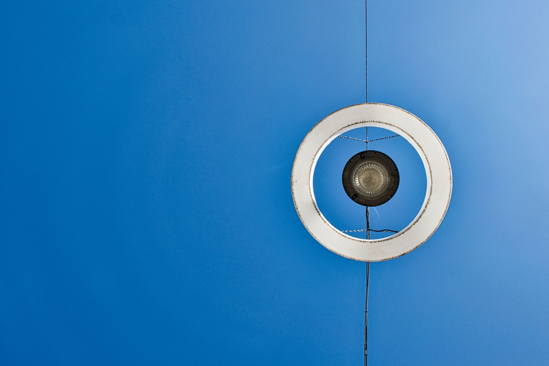 Clear blue sky with a white circular fixture centered on a vertical seam