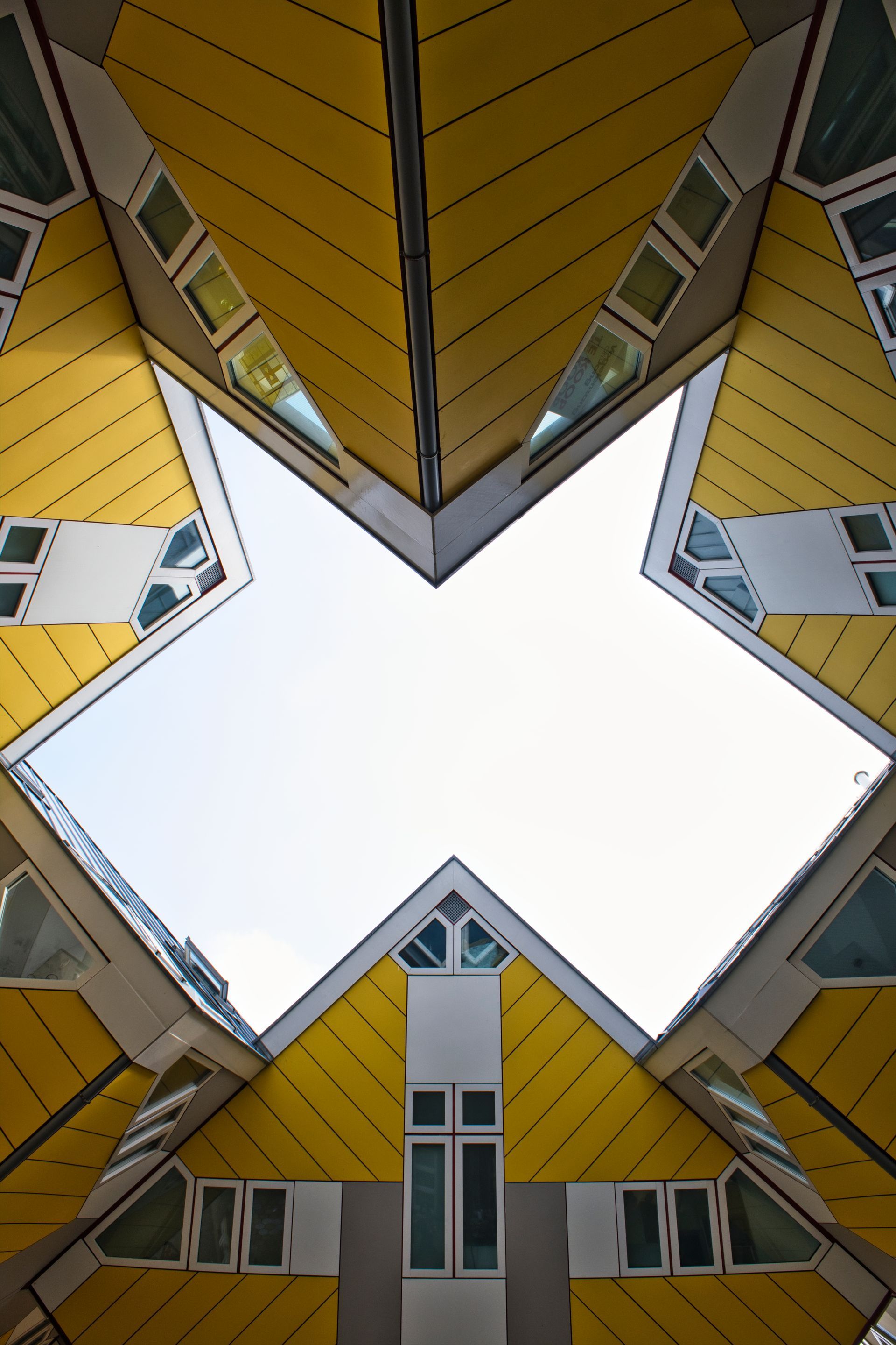 Upward view of colorful geometric building facades framing a bright white sky opening