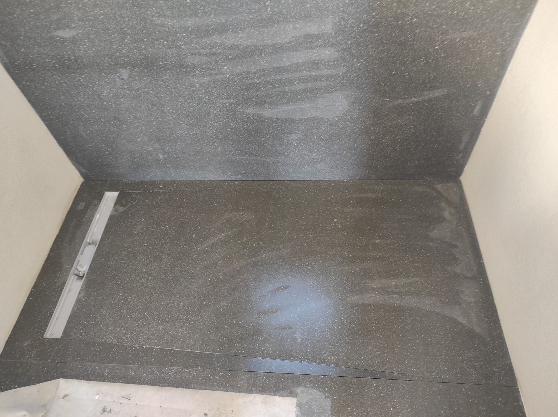 Contenitore vuoto di colore grigio con fondo nero e luce riflessa dalla parete di fondo.