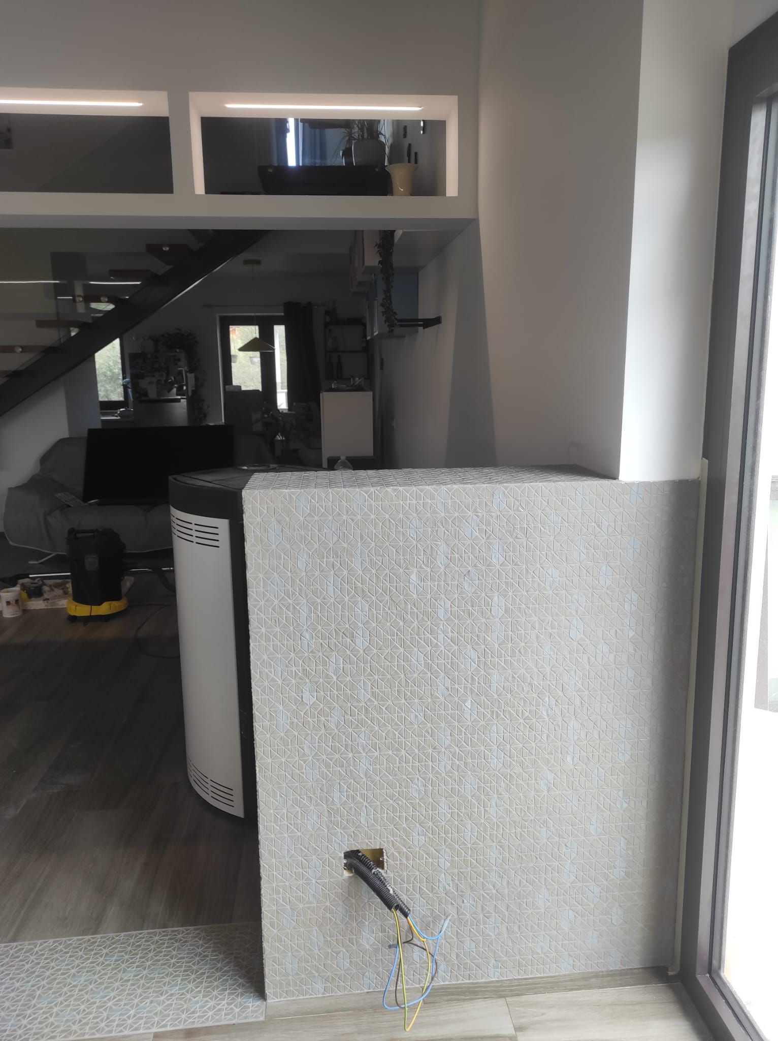 Interno moderno con parete divisoria curva e texturizzata, scala e ampia finestra o porta a vetri.
