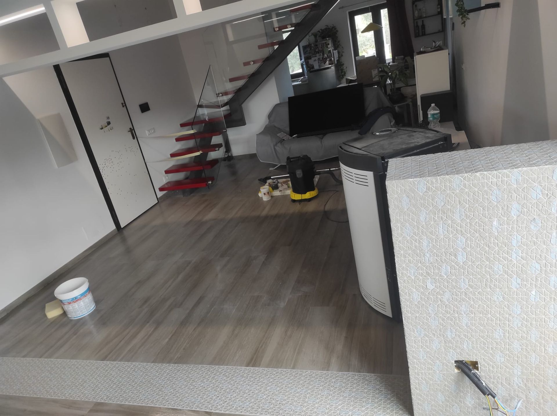 Interno di un appartamento moderno con scala, pavimento grigio e prodotti per la pulizia sul pavimento.