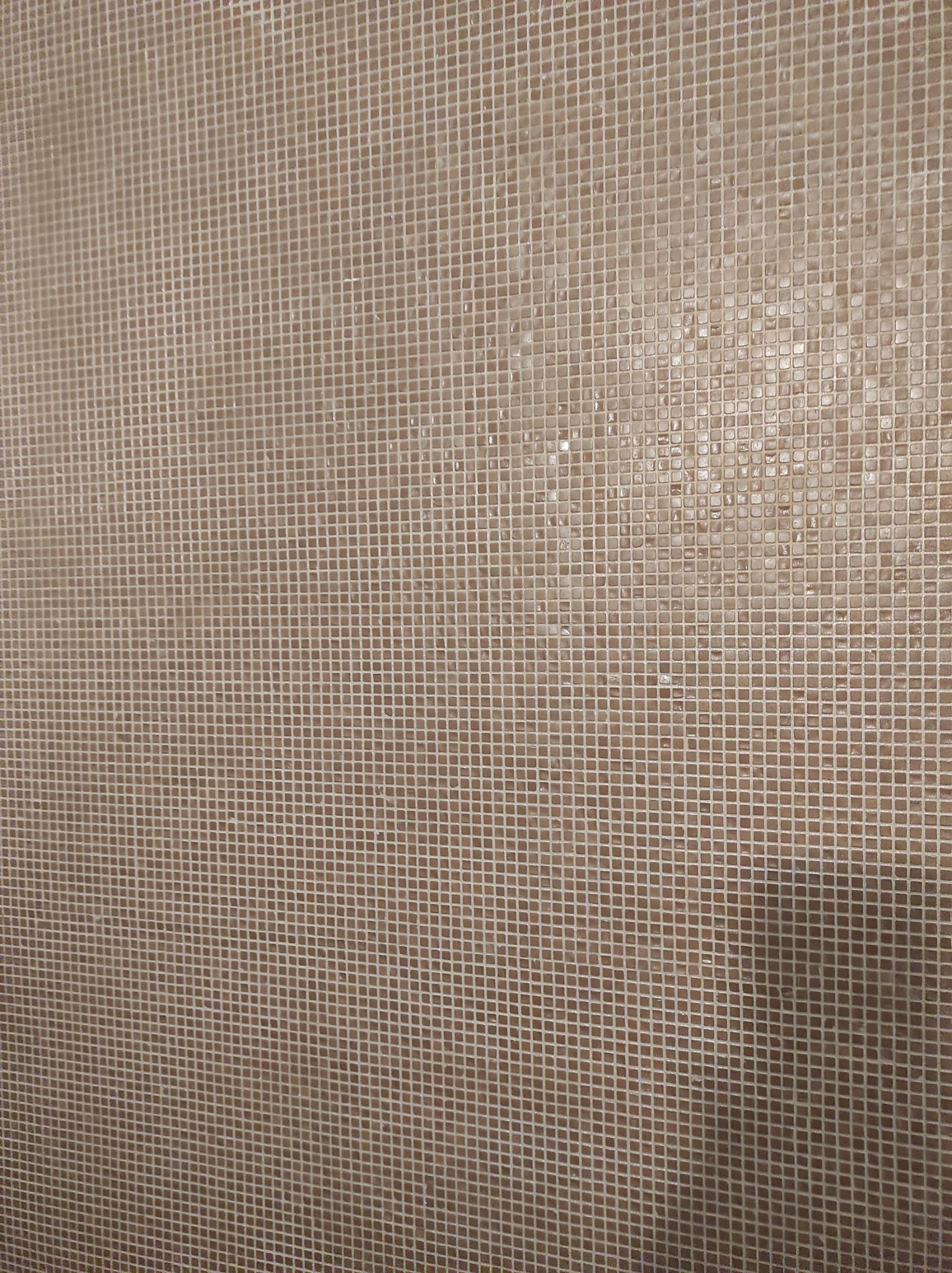 Primo piano di un tessuto beige intrecciato con una leggera ombra diagonale.