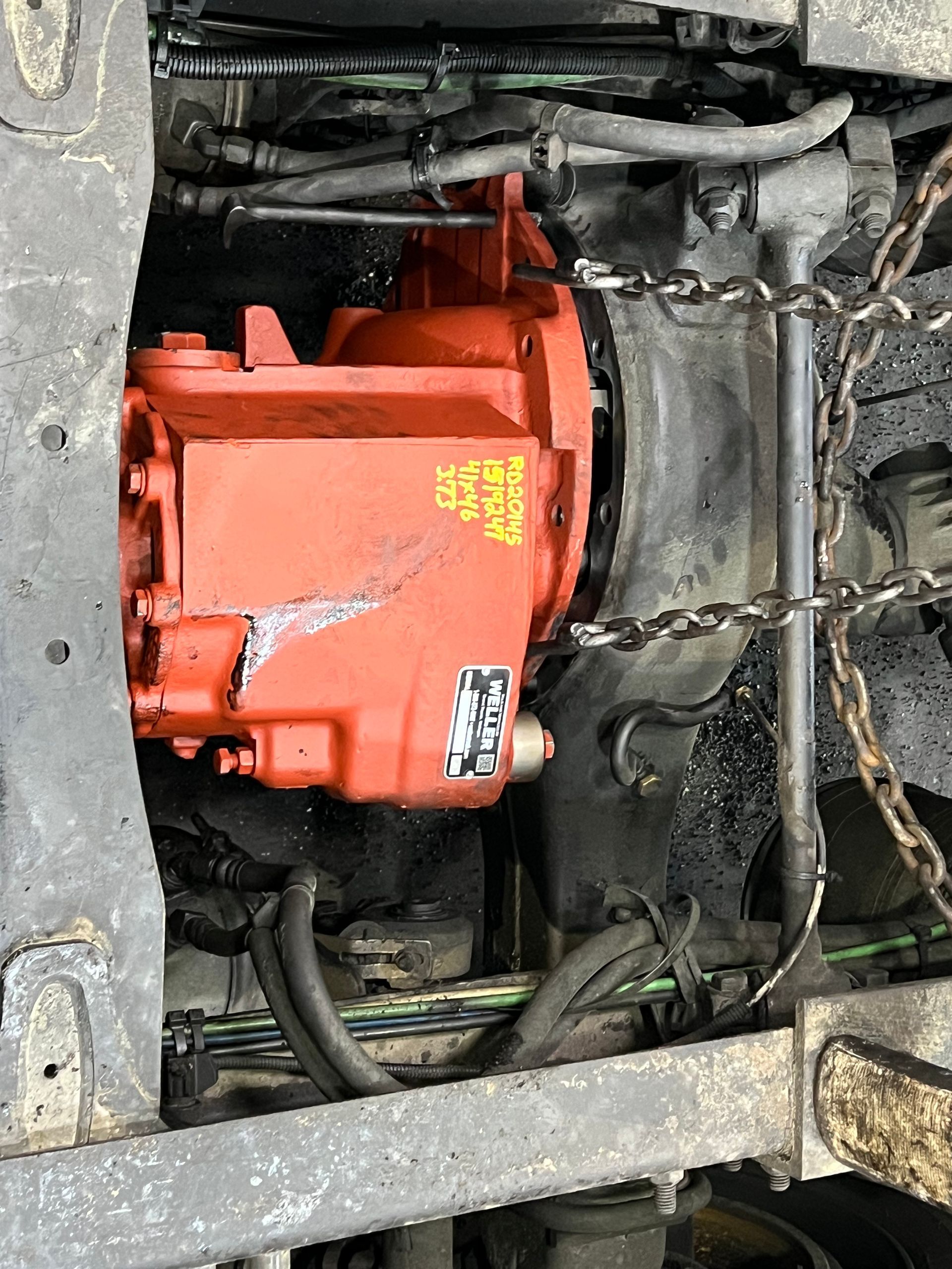 Orange truck transmission, surrounded by parts and chains.