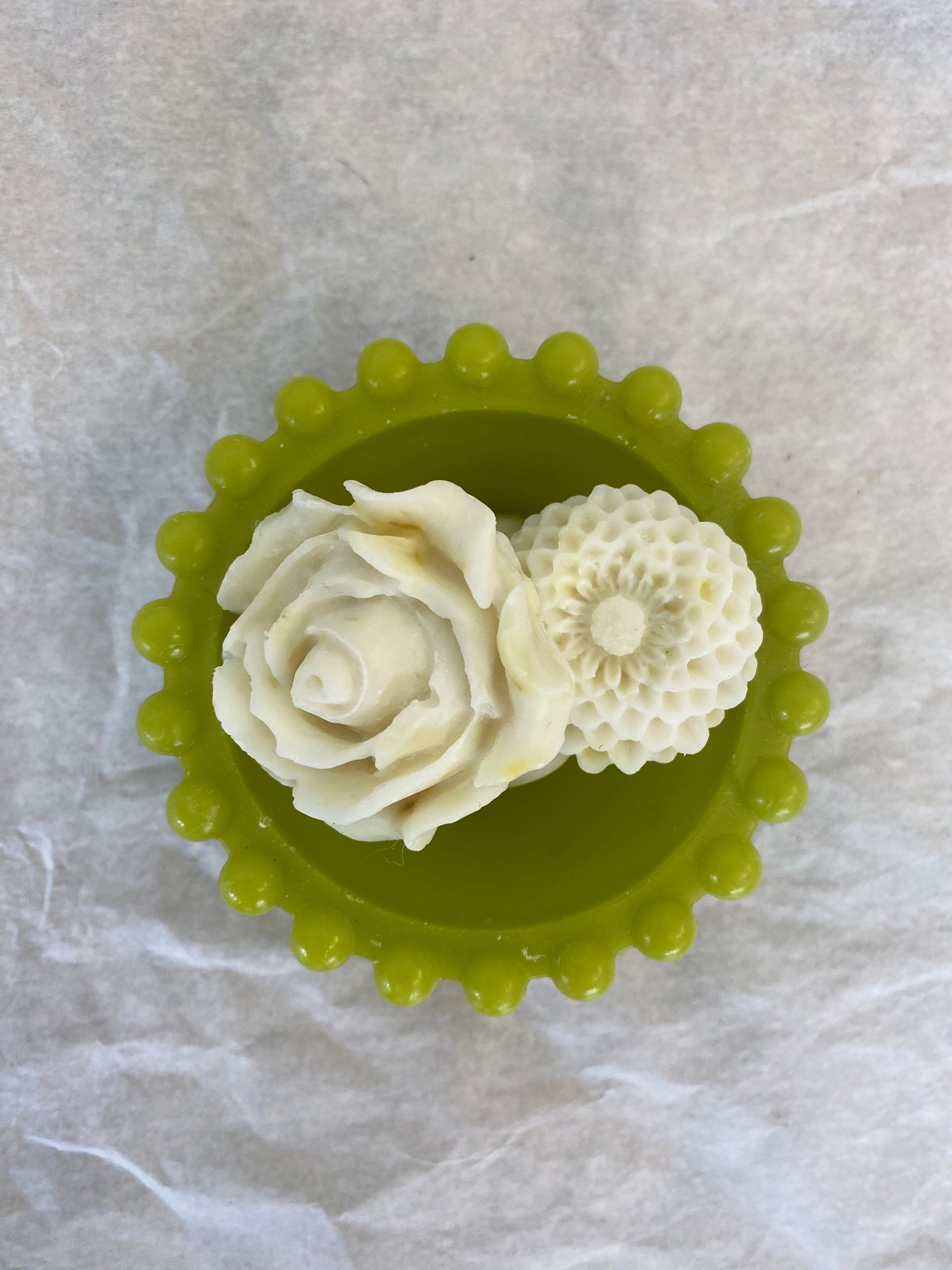 Un bol vert avec deux fleurs blanches dedans