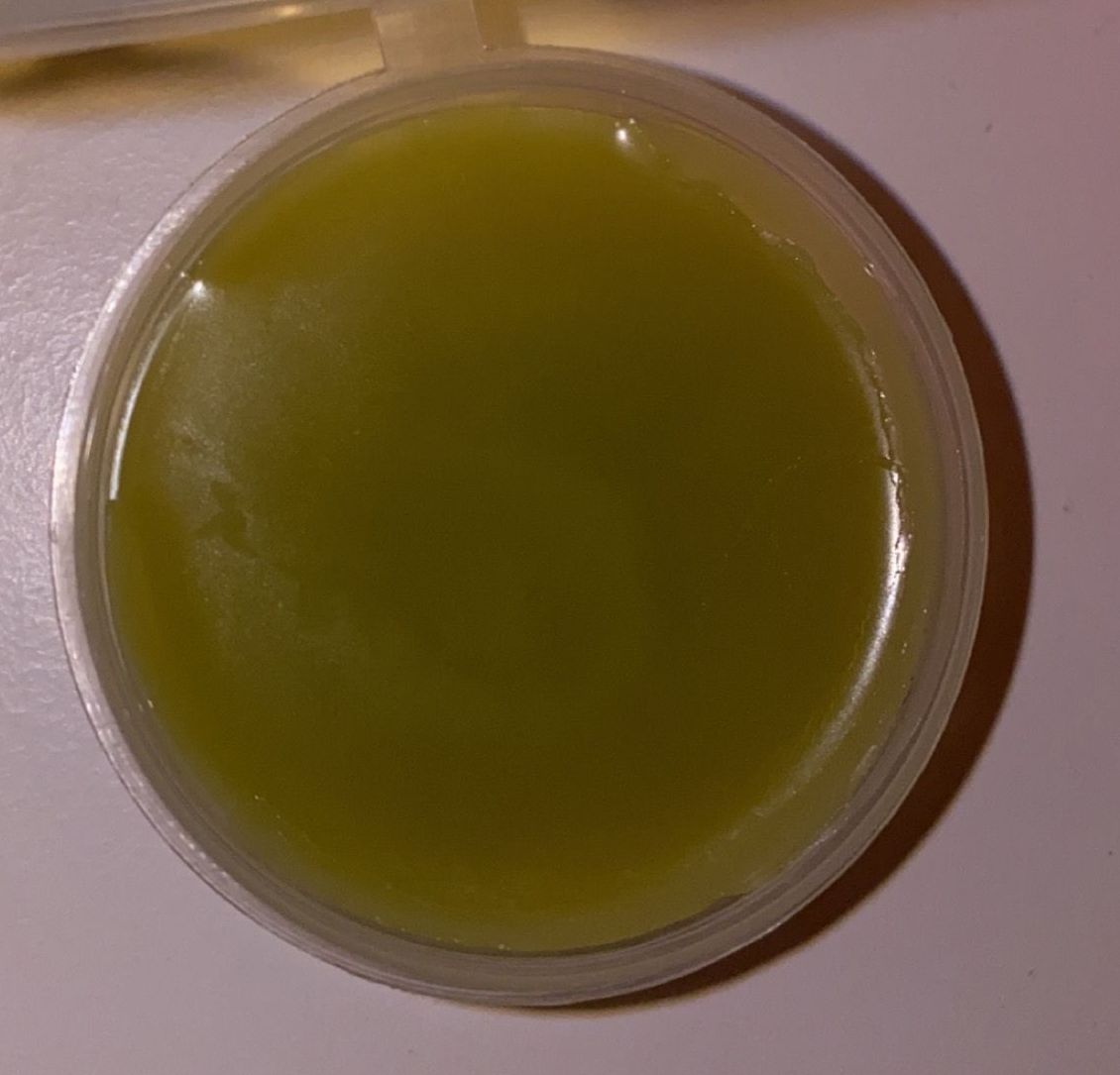 Un petit récipient en plastique rempli de liquide vert