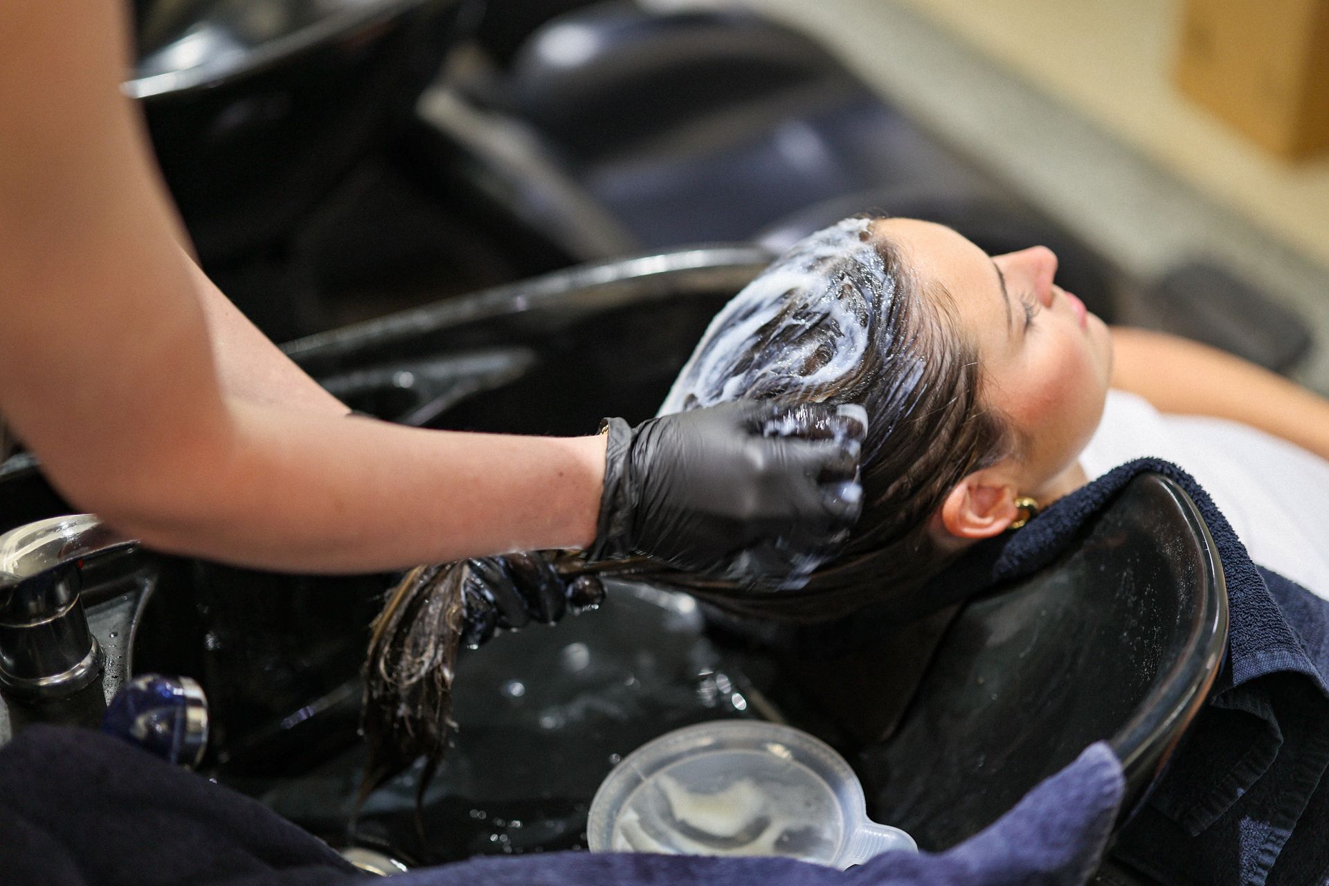 A lady enjoying a luxury hair treatment at a backwash basin