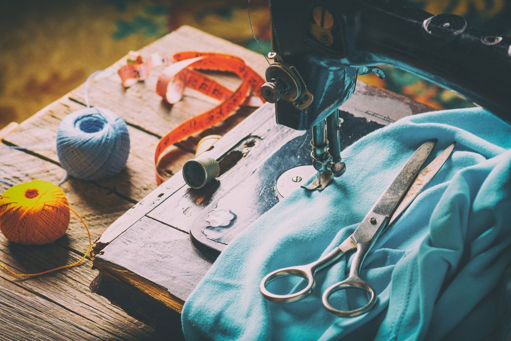 A Sewing Machine Is Sitting On A Wooden Table Next To Scissors And Yarn — The Sewing Machine Doctor In Noosa, QLD