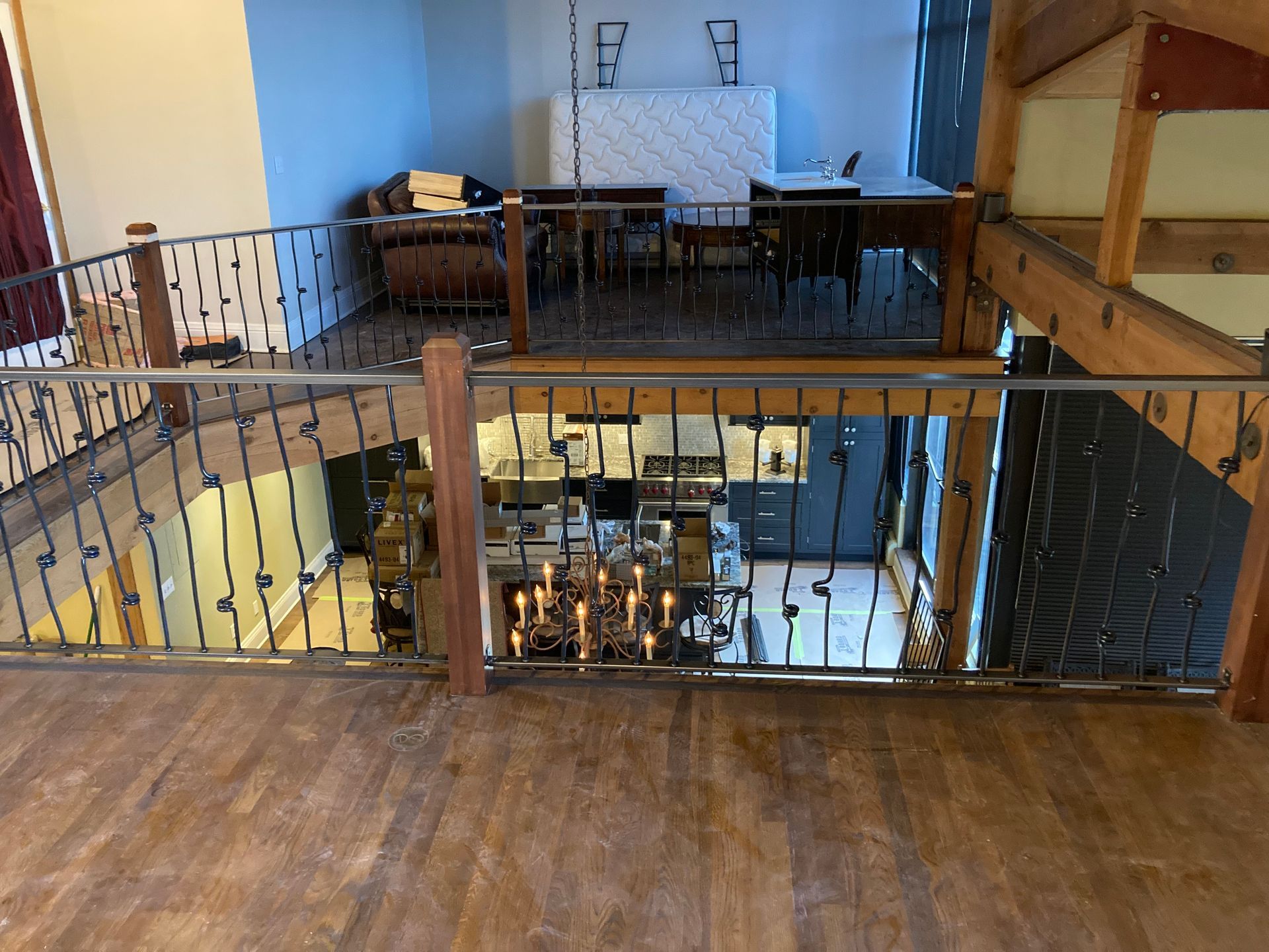 Loft interior: wrought iron railing, wood floors, overlooking kitchen, dining, and seating area.