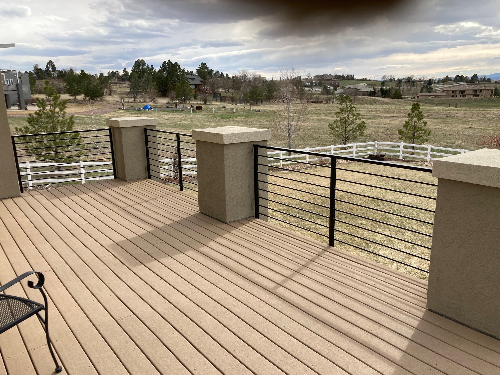 Black railing on a concrete porch with steps leading to a home's front door.