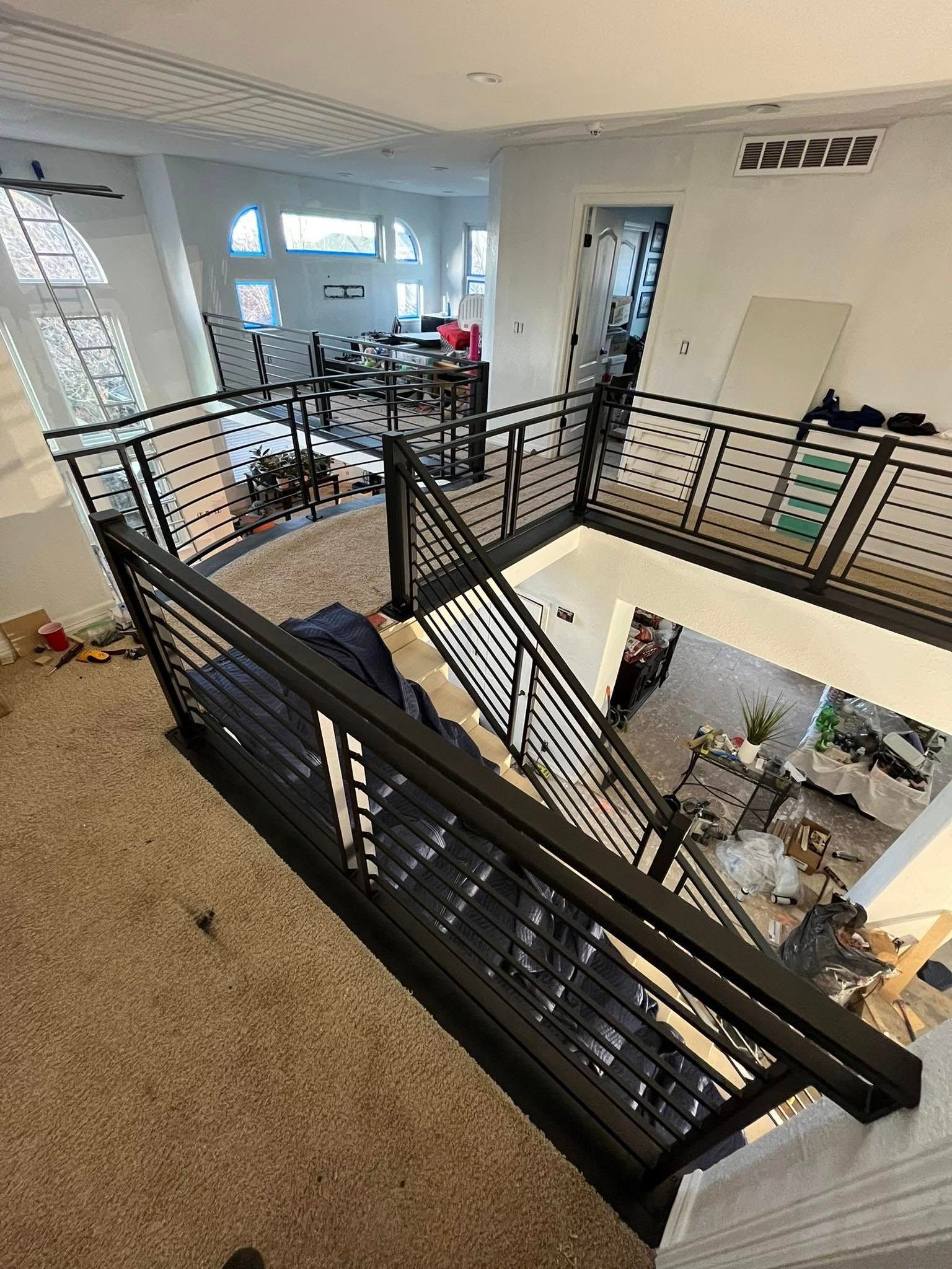 A modern, multi-level home interior with black railings and carpet.