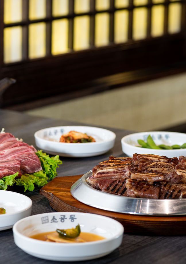 Korean barbecue spread with sliced meat, dipping sauces, and side dishes on a wooden table