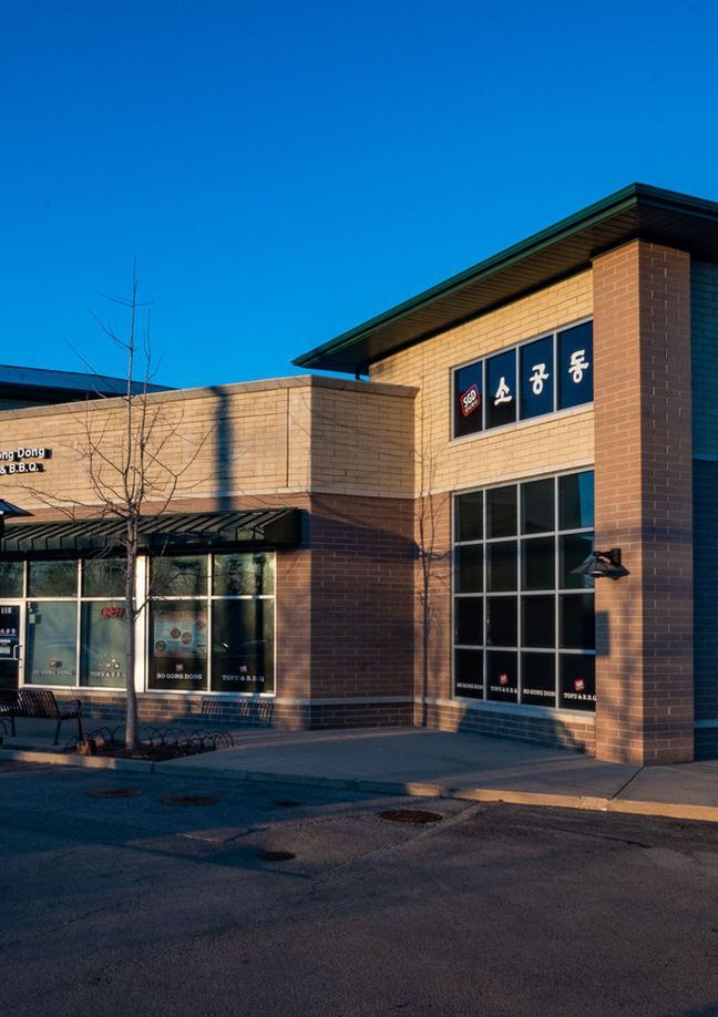 Brick building with large windows and a blue sign at dusk
