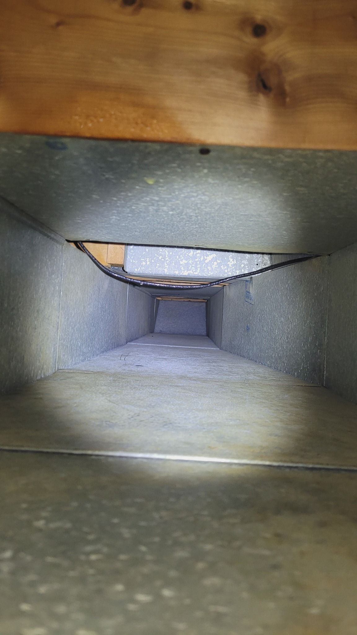 A close up of a metal duct with a hole in it.